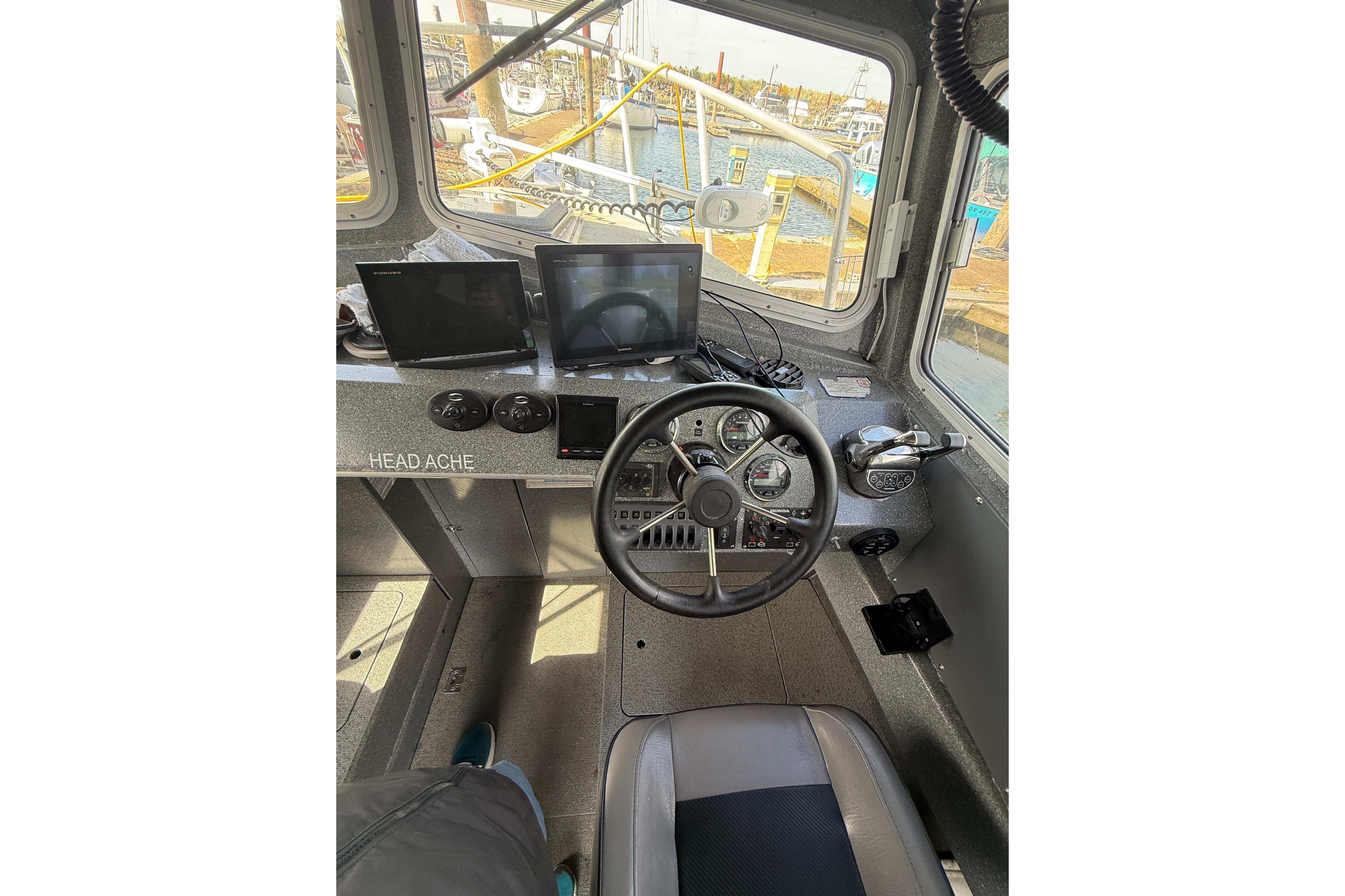 Interior view of 2016 North River 29 Offshore boat cockpit with steering wheel and navigation screens.