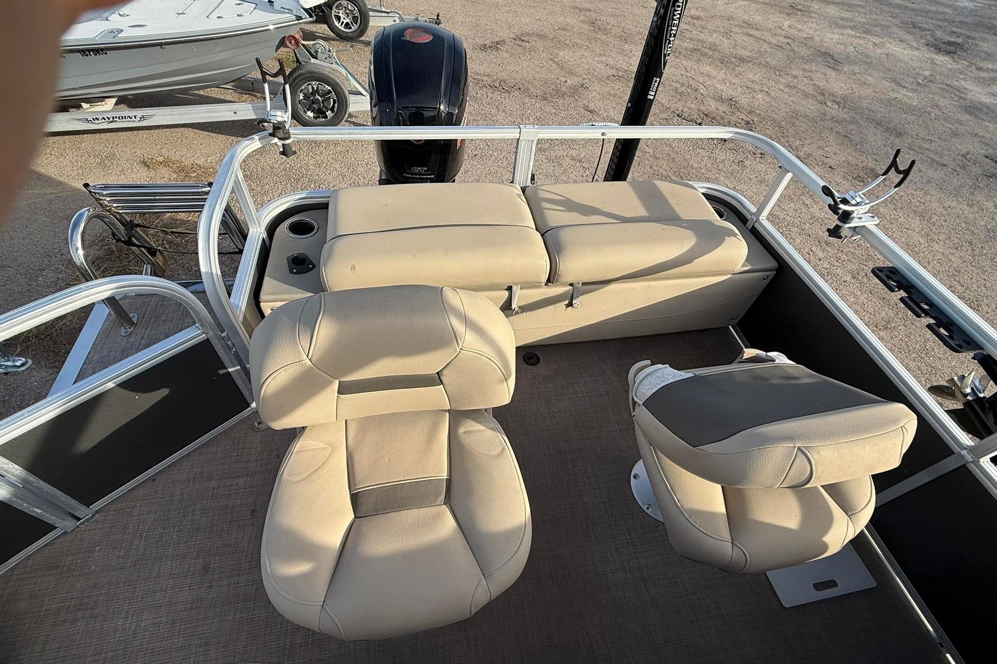 2023 Sun Tracker Fishin' Barge 22 DLX interior with beige seating and fishing rod holders.