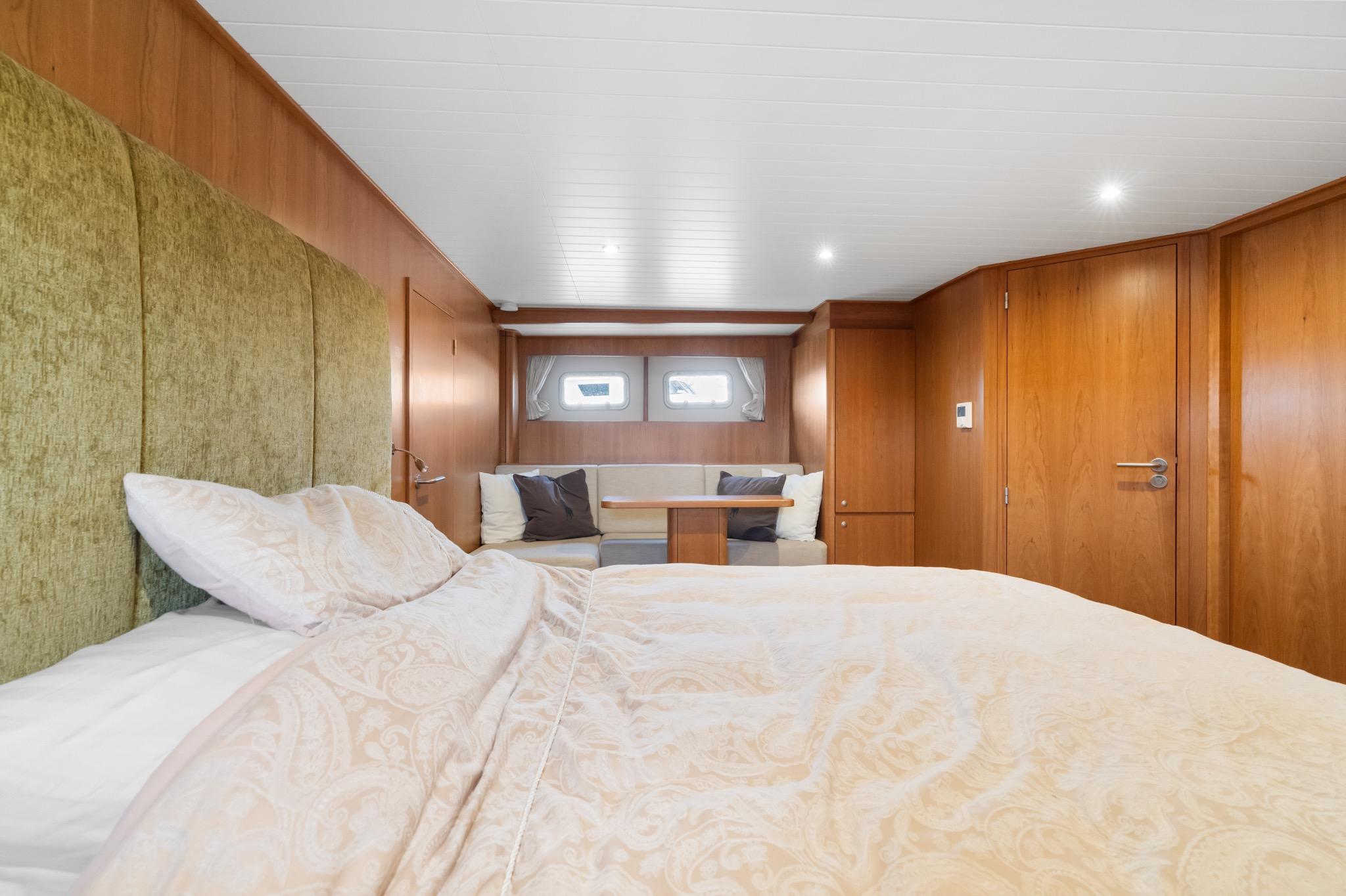 Luxurious bedroom interior of 2022 Alm Trawler Delfino 64 yacht, featuring elegant wood paneling.