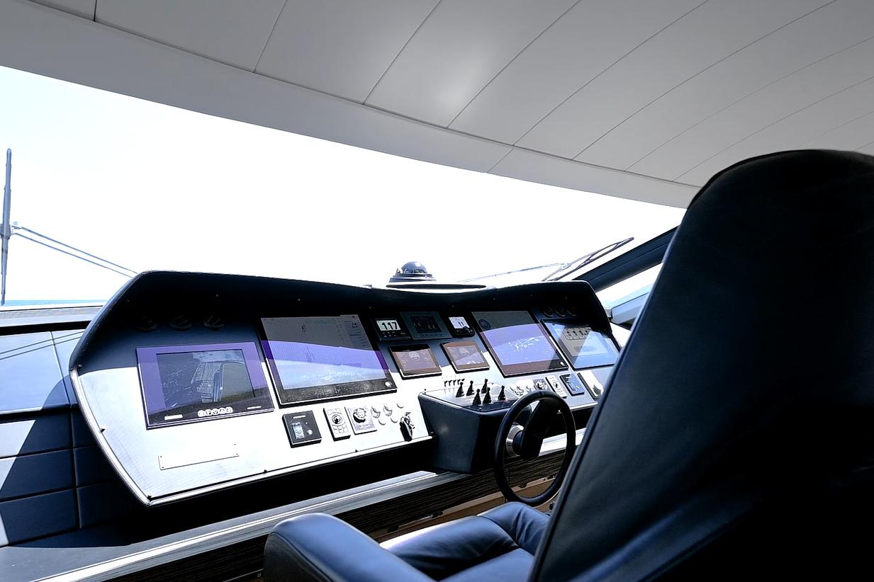 Control panel of a 2015 Pershing 92 yacht with multiple screens and steering wheel.
