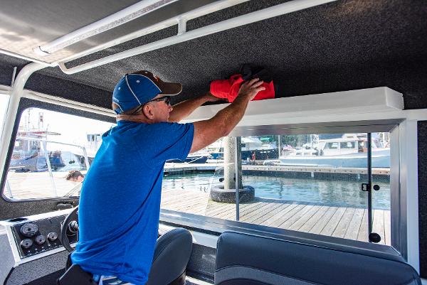 Man organizing gear inside a 2023 Spartan 220 Maximus Pro boat at a marina.