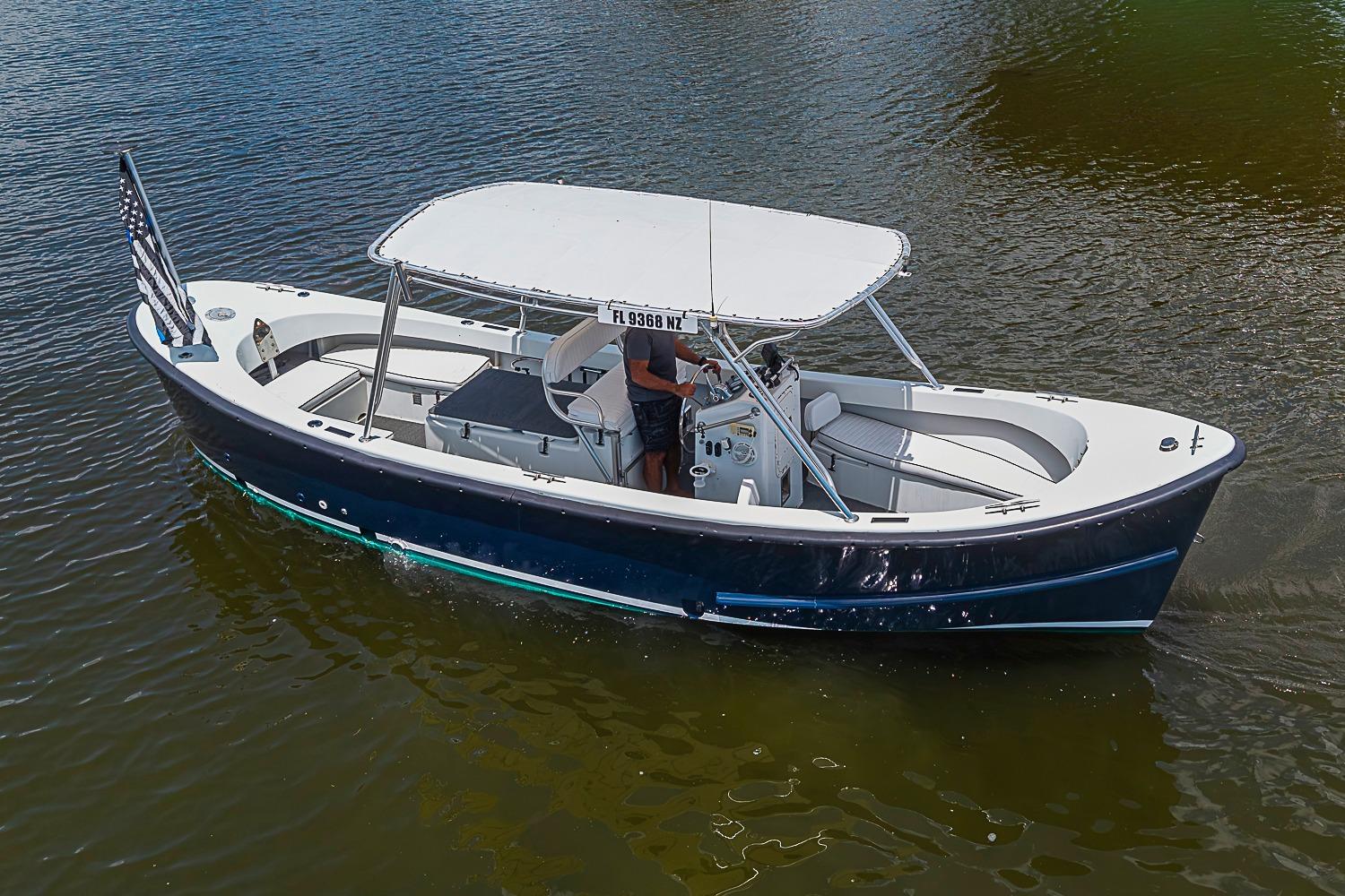 Custom 1969 boat with canopy cruising on water, displaying an American flag.