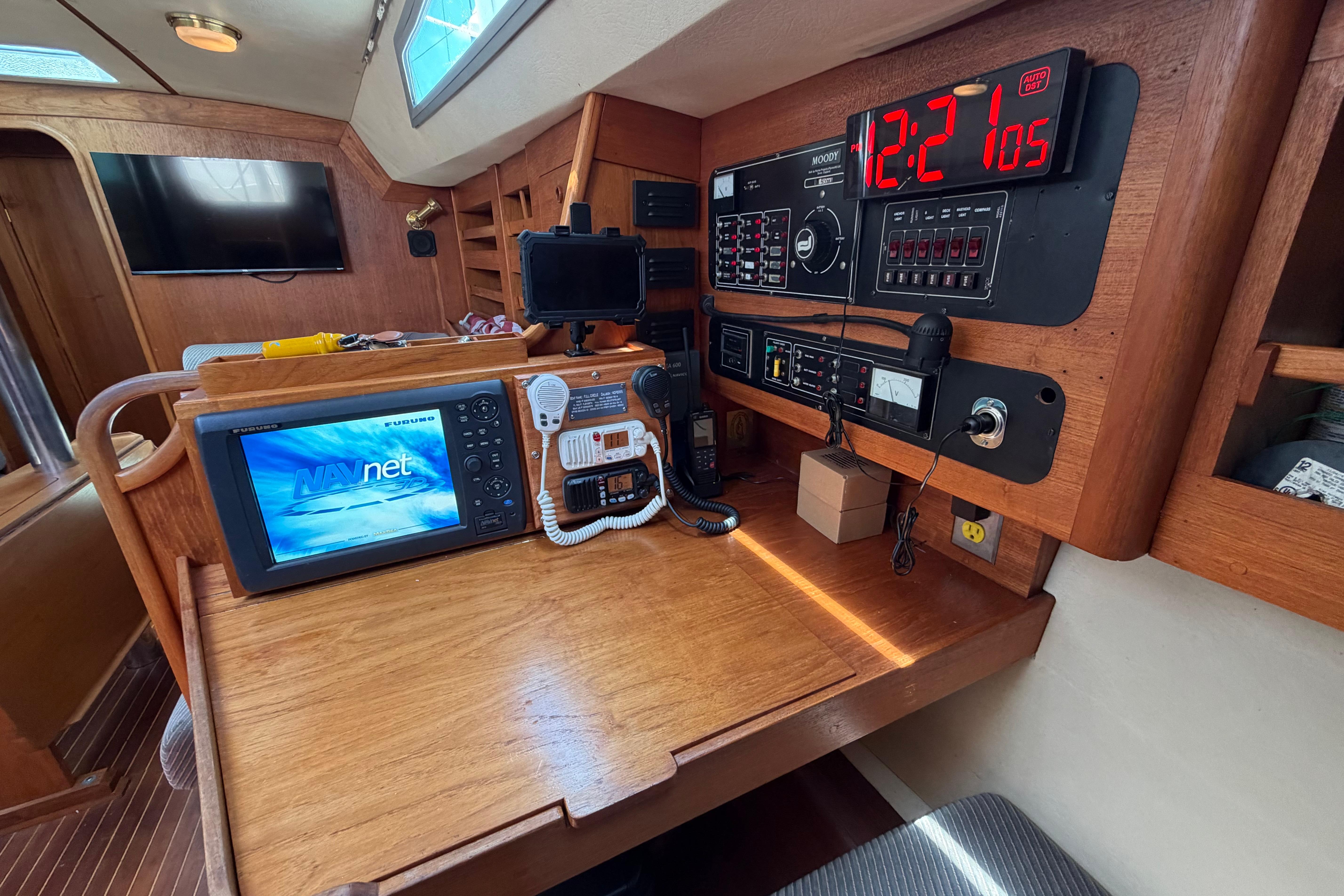 Navigation station on a 1987 Moody 376 yacht with electronic equipment and wooden interior.