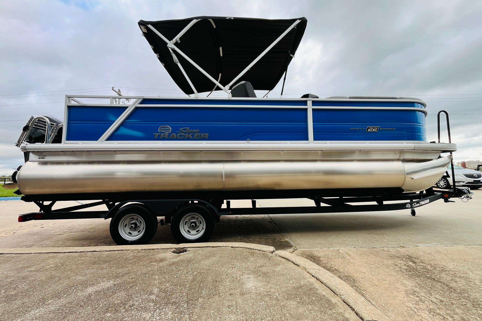 2026 Sun Tracker Party Barge 22 RF DLX pontoon boat on trailer, blue and silver design.