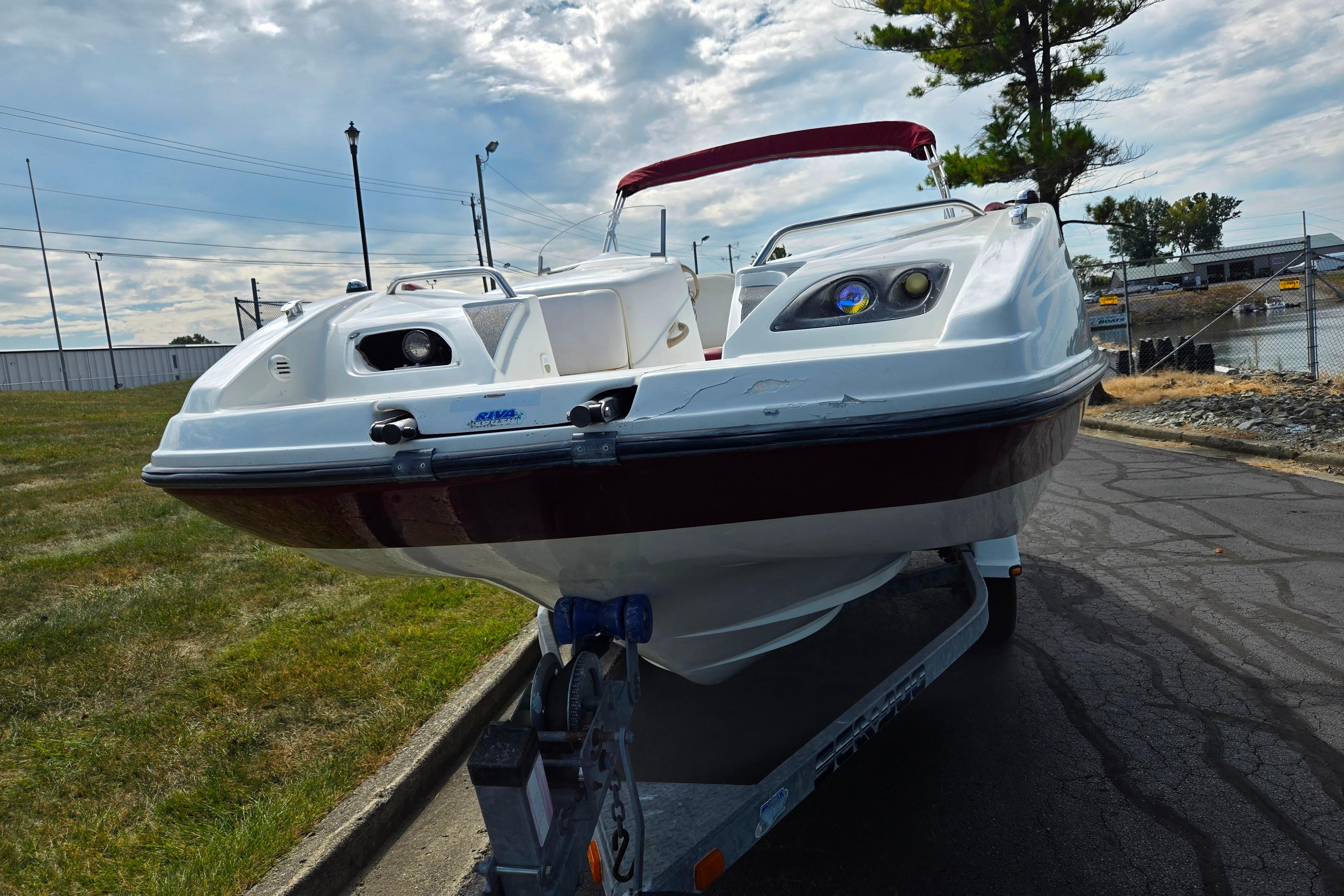 2004 Sea-Doo Islandia sport boat on trailer, parked near waterfront under cloudy sky.