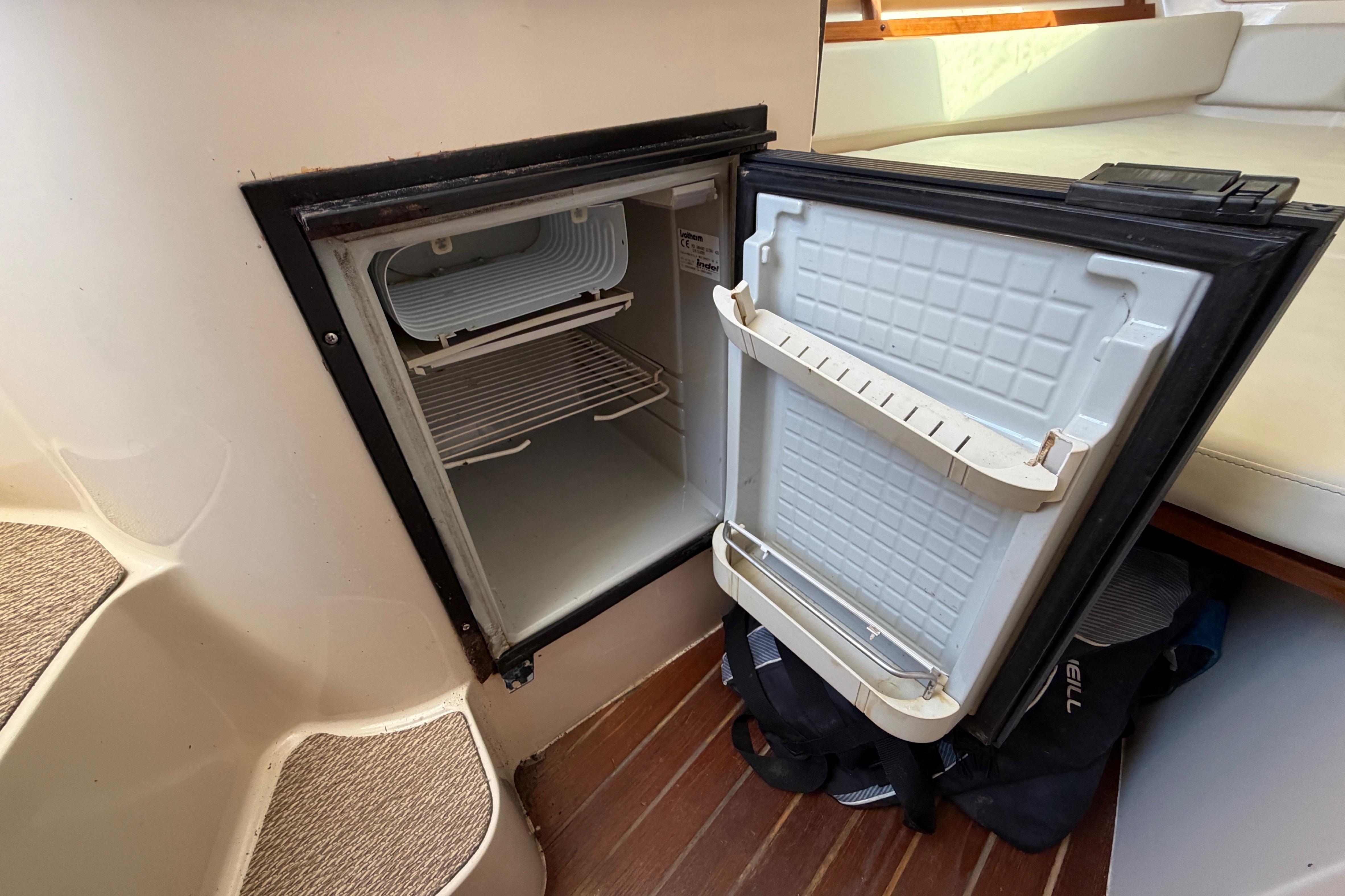 Open refrigerator inside 2006 Grady-White Sailfish 282 boat cabin, showcasing interior storage space.