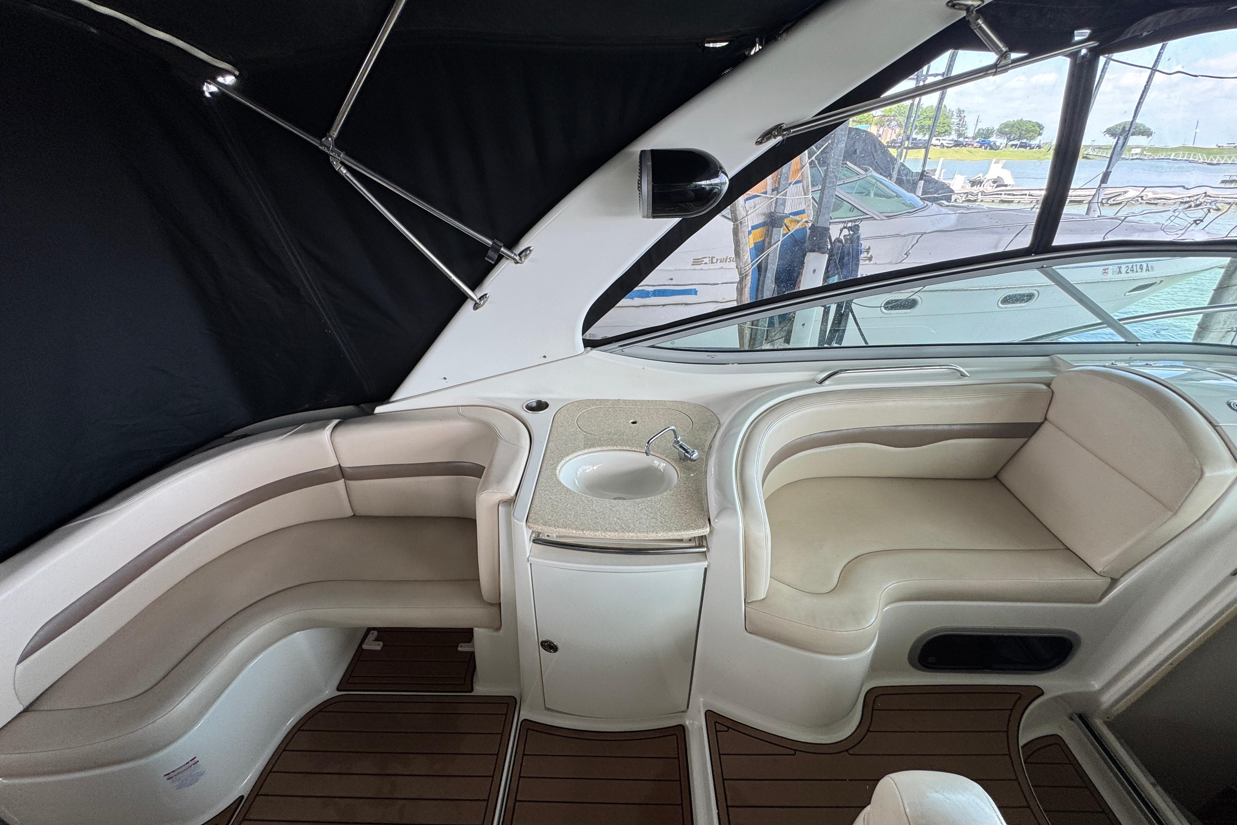 2006 Chaparral 330 Signature boat interior with seating and sink, docked by the water.