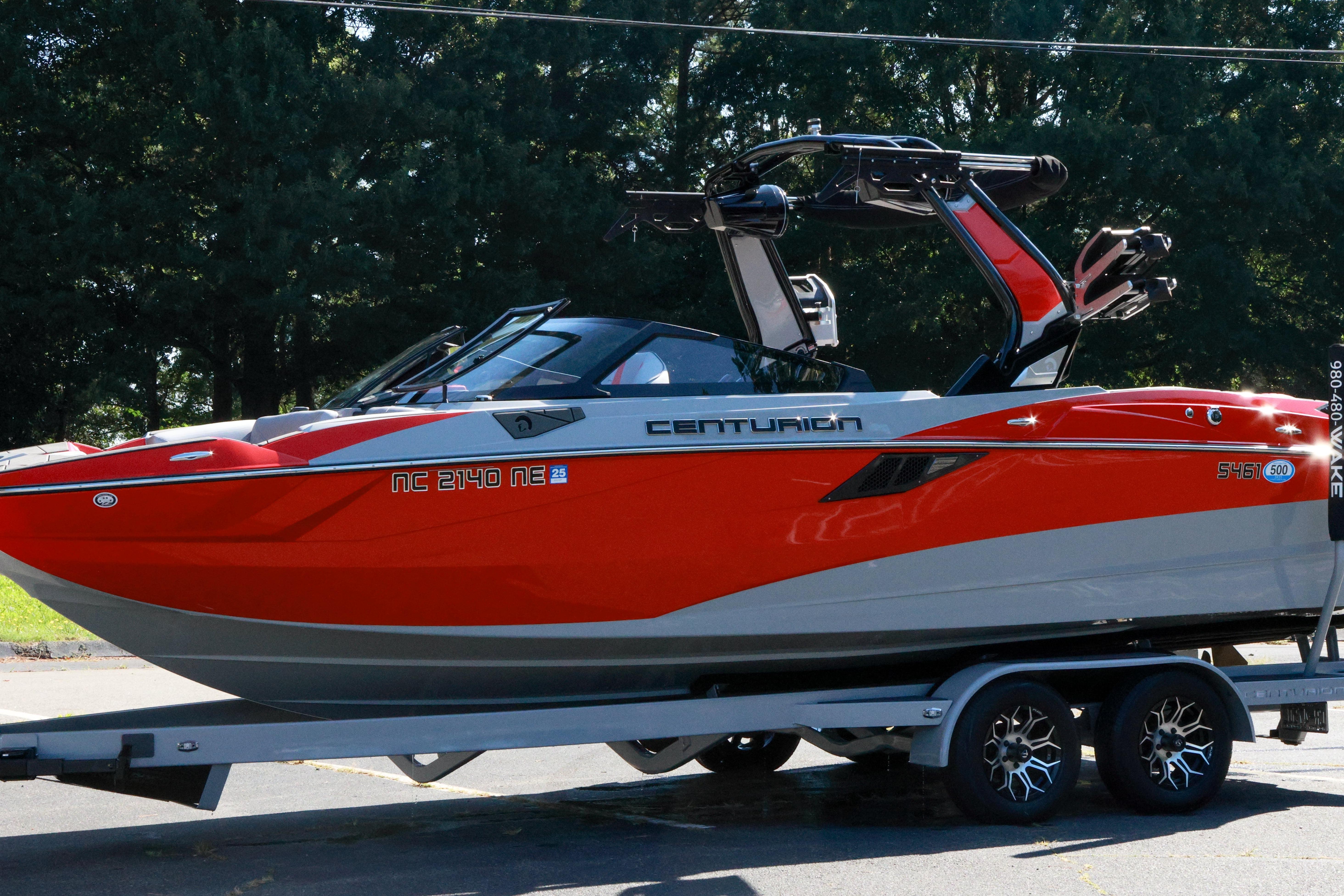 2024 Centurion Fi23 boat in vibrant red on a trailer, parked outdoors.