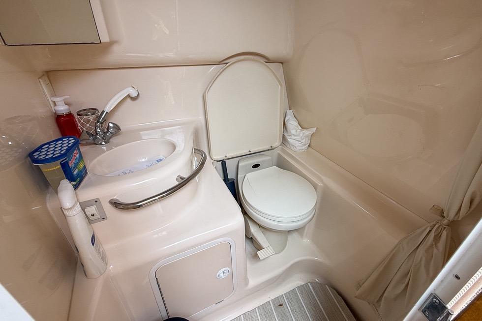 1999 Sea Ray 290 Sundancer bathroom with sink, toilet, and storage cabinet.