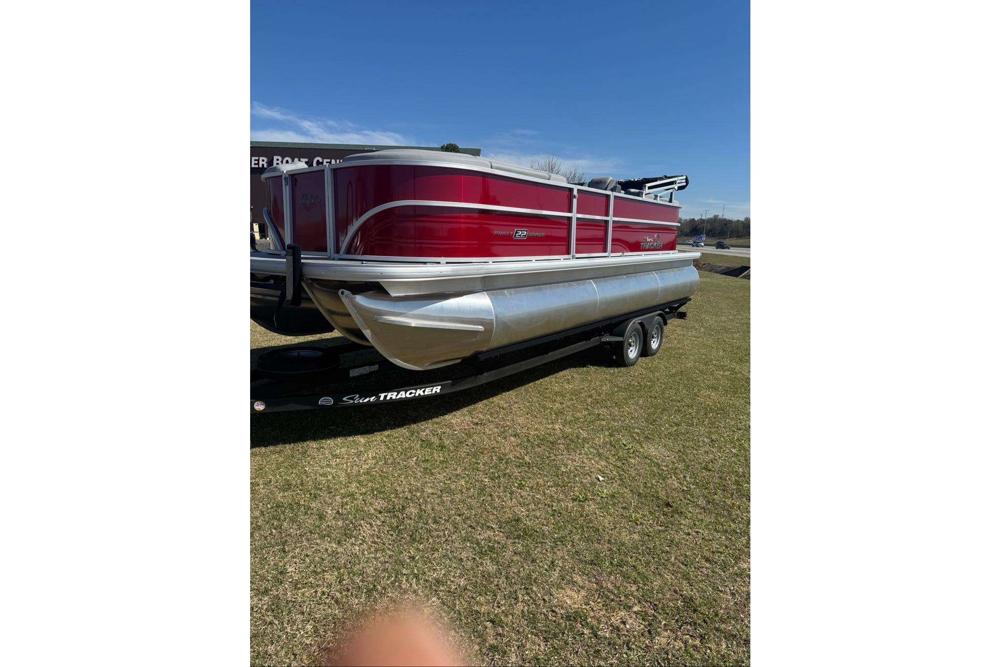 2026 Sun Tracker Party Barge 22 XP3 pontoon boat on trailer, parked on grass.