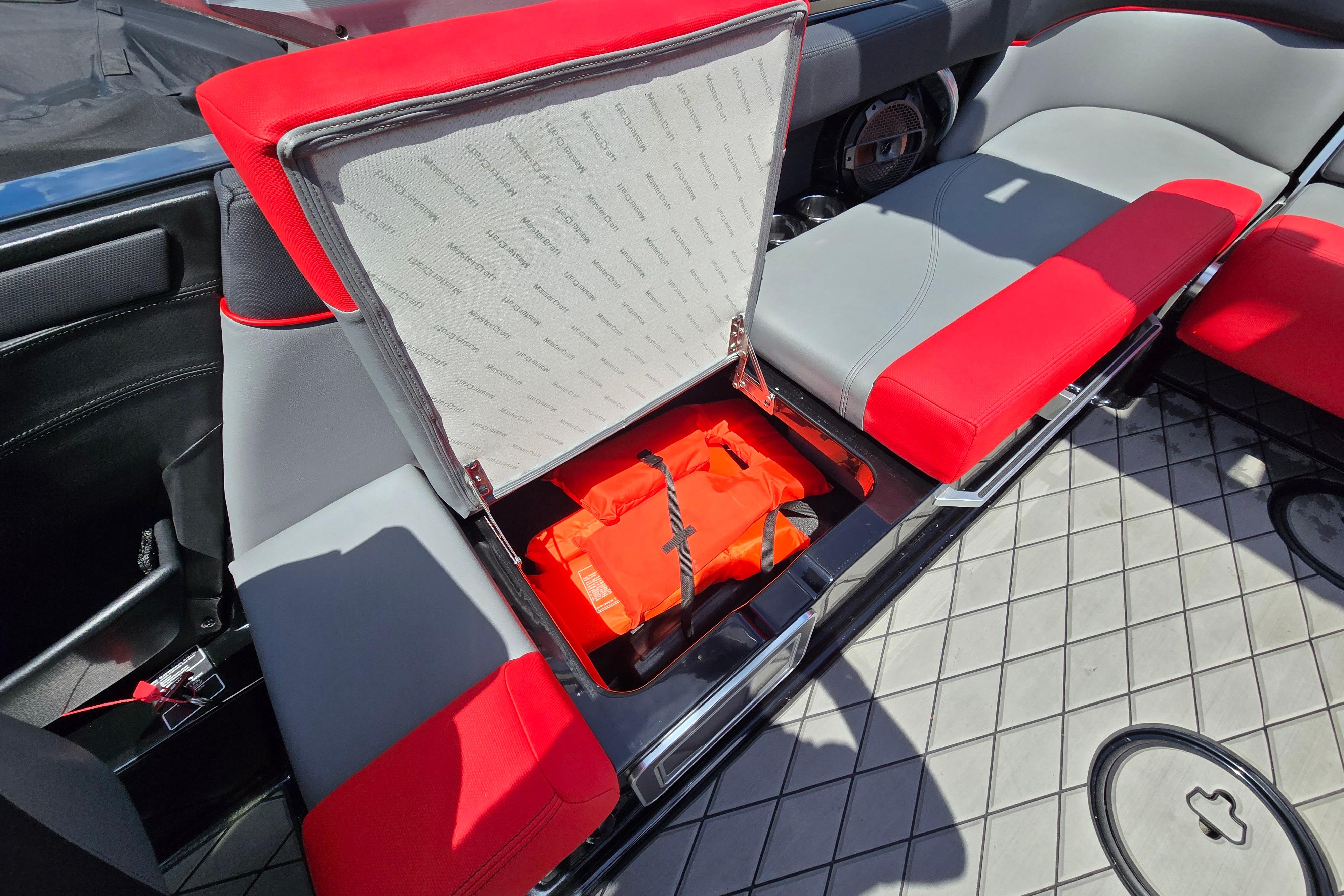 2019 MasterCraft XT25 boat interior with red and gray seating, open storage compartment.