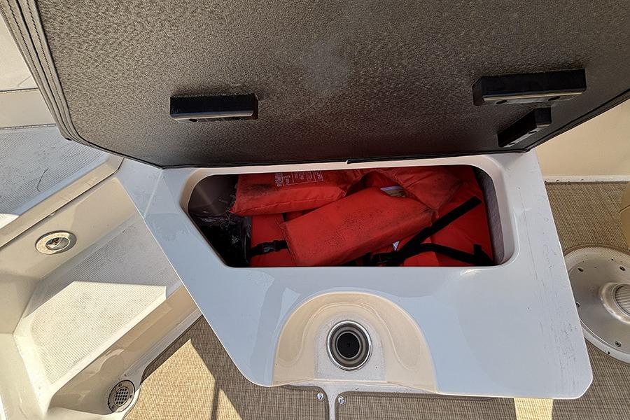 Storage compartment with life jackets on a 2019 Sea Ray SPX 230 Outboard boat.