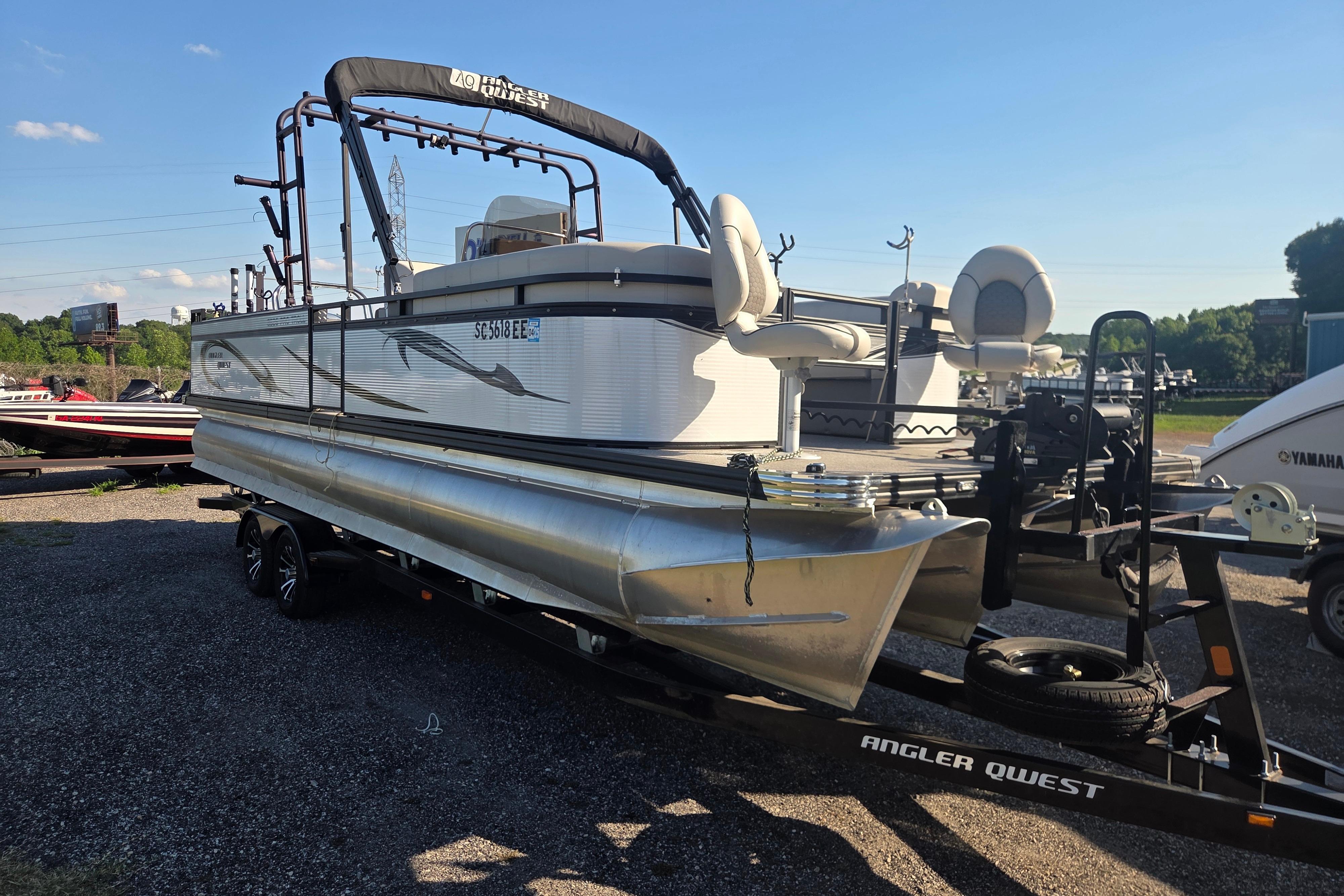 2024 Angler Qwest 8526 Pro Troll pontoon boat on trailer, parked outdoors.