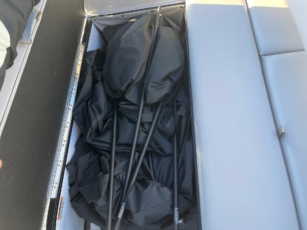 Storage compartment of 2024 Starcraft SLS3 boat with black cover and poles.