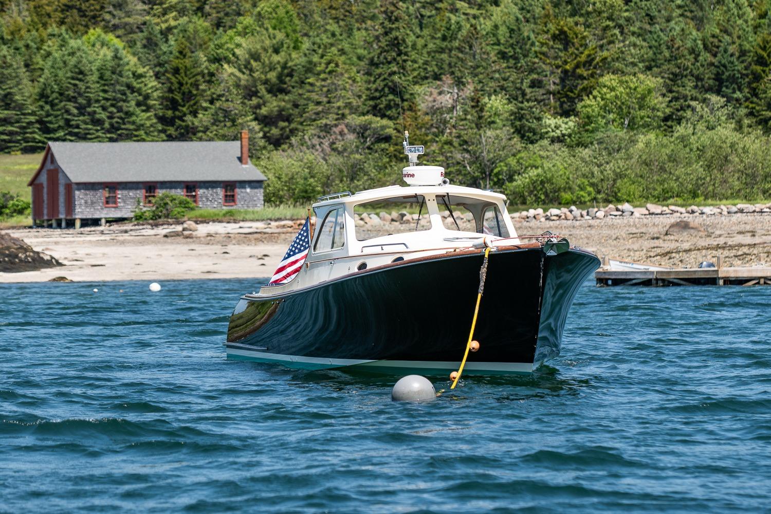 2001 Hinckley Picnic Boat 36 Classic moored near a rustic shoreline cabin.