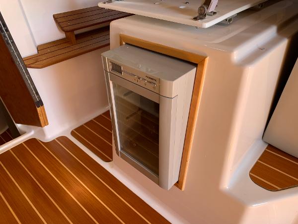 2021 Cutwater C-32 CB interior with compact fridge and wooden flooring.