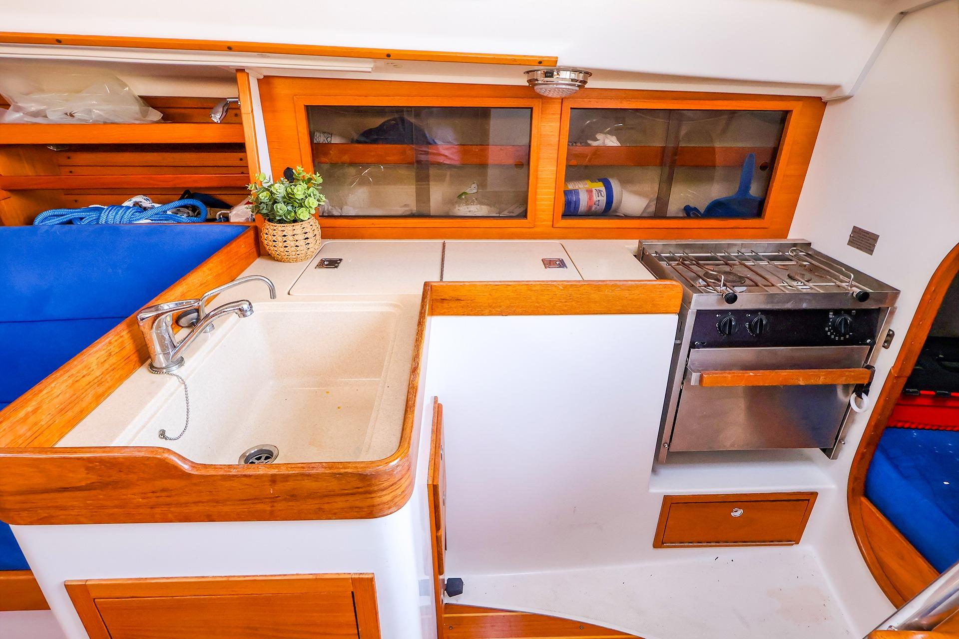 2001 J Boats J/32 yacht interior with kitchen sink, stove, and wooden cabinetry.