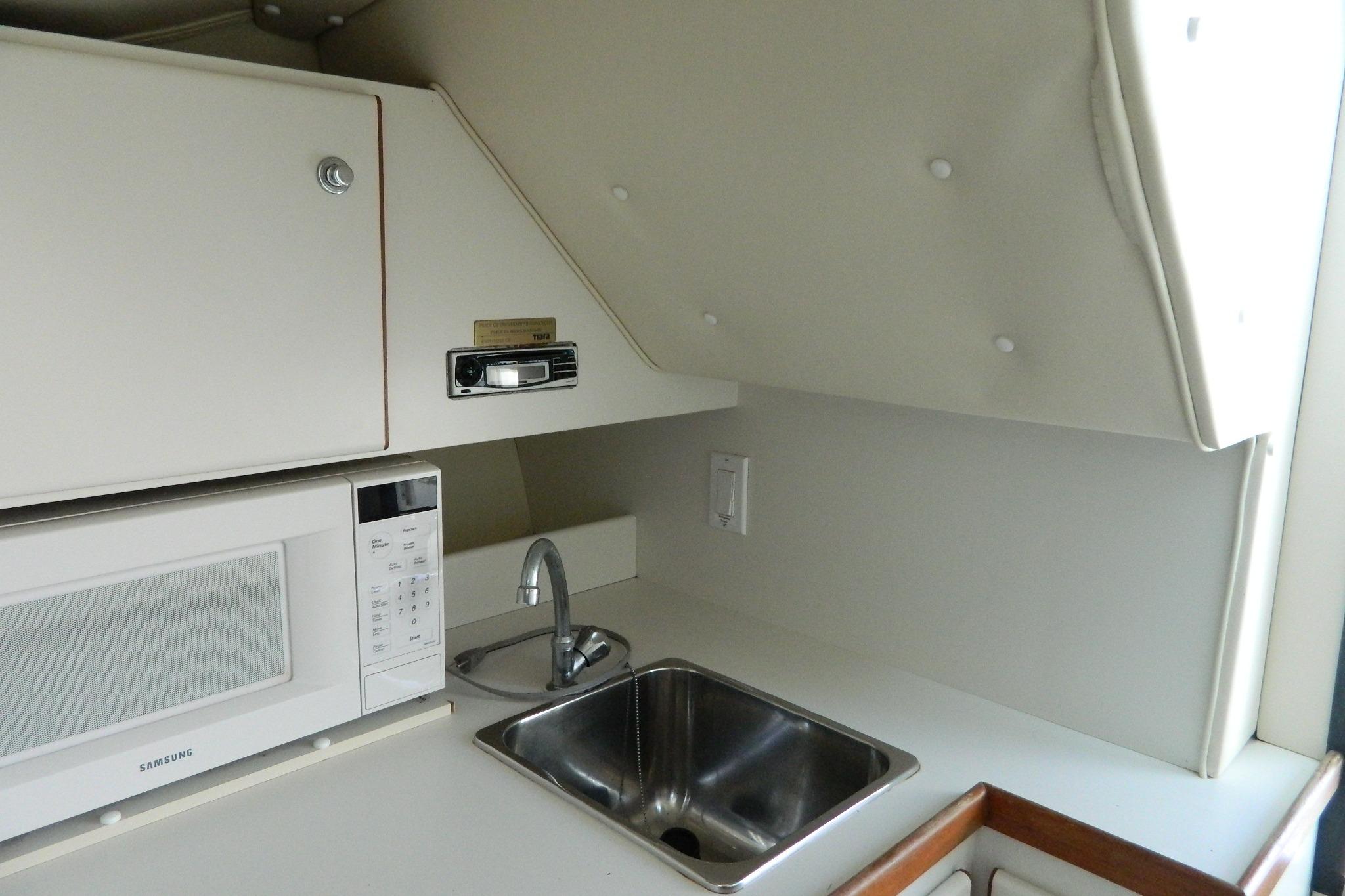 1999 Tiara Yachts 2900 Coronet interior with sink and microwave in compact kitchen area.