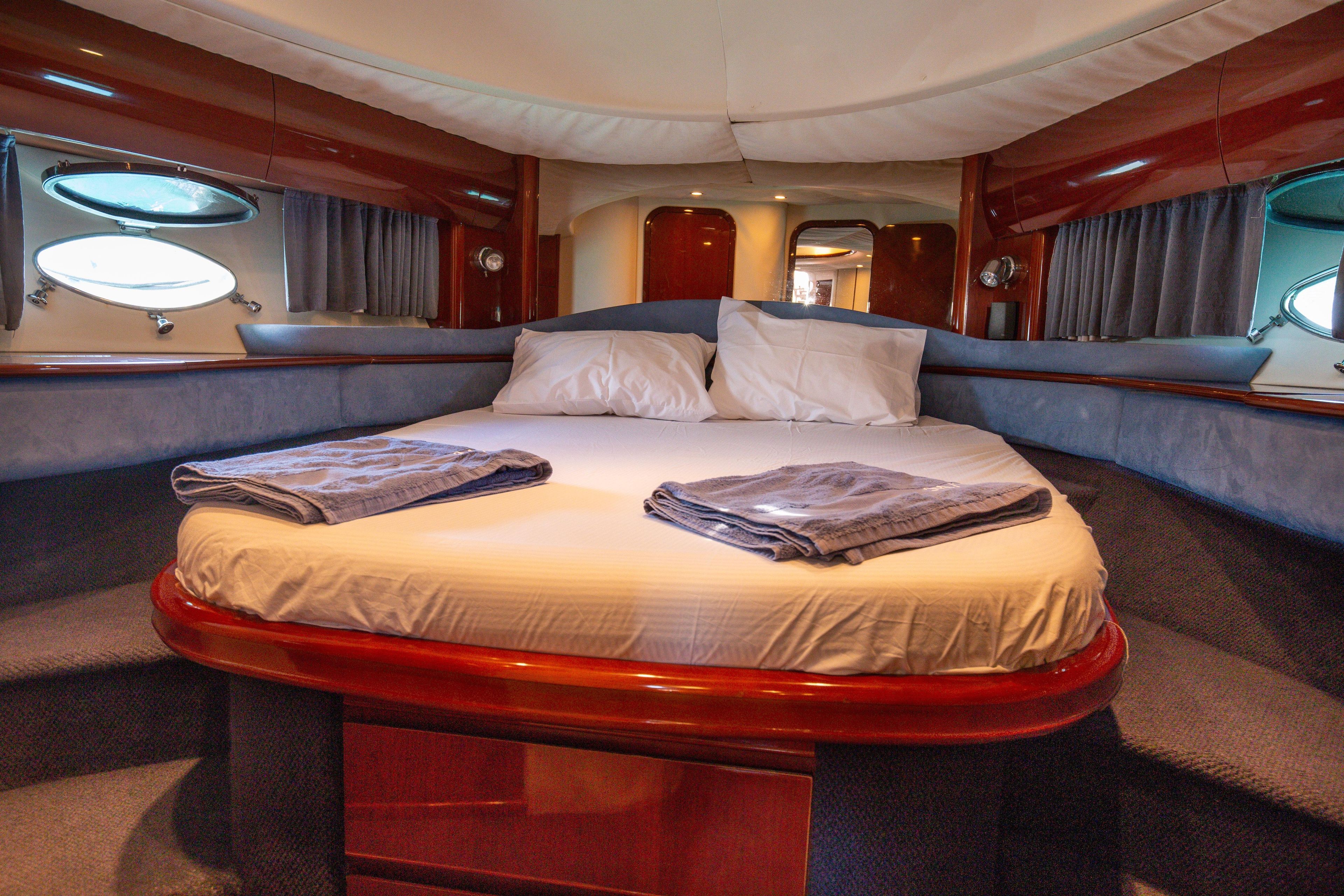 Luxurious cabin interior of 2004 Princess V65 yacht with cozy bed and porthole windows.