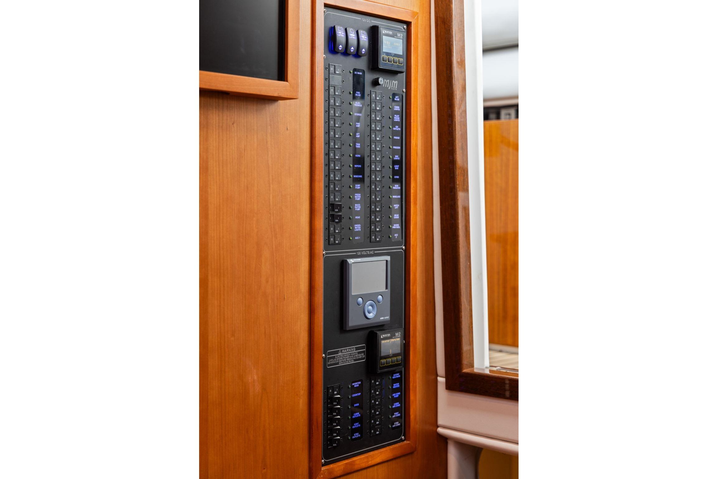 Electrical control panel on 2024 MJM 42 yacht, featuring switches and digital display.