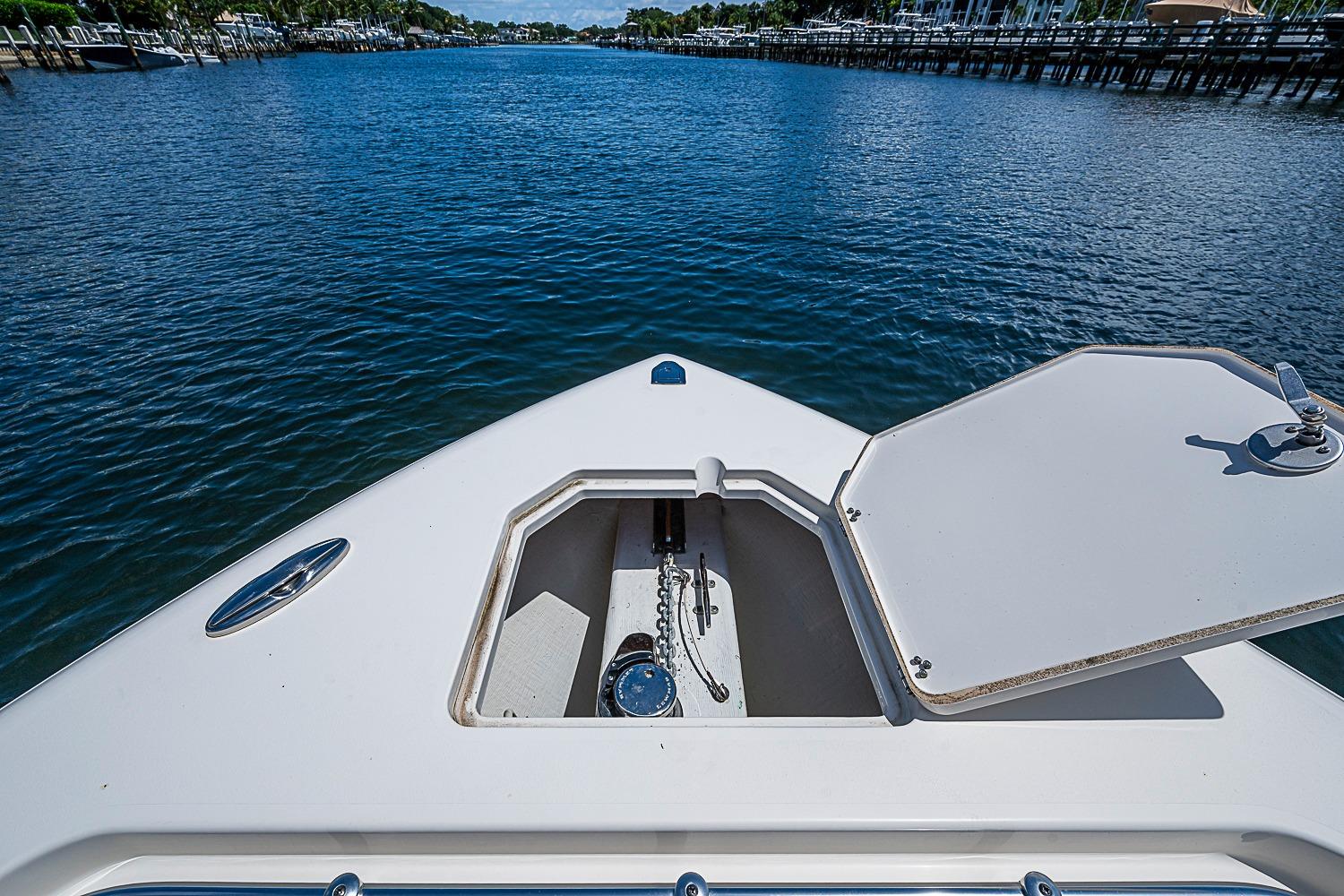 2019 Cobia 320 Center Console boat with open anchor hatch on calm water.