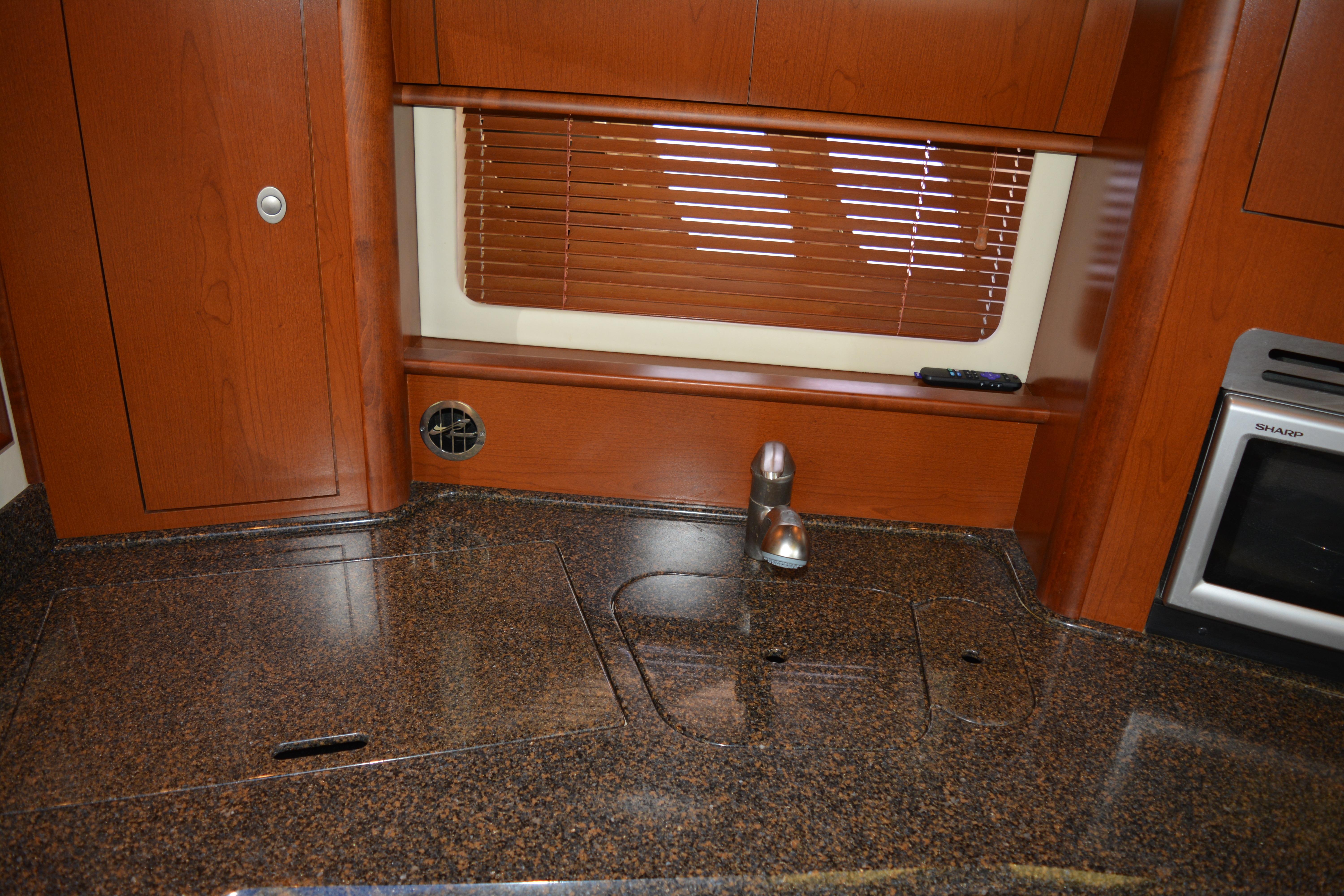 2007 Sea Ray 44 Sundancer kitchen with granite countertop and wooden cabinetry.