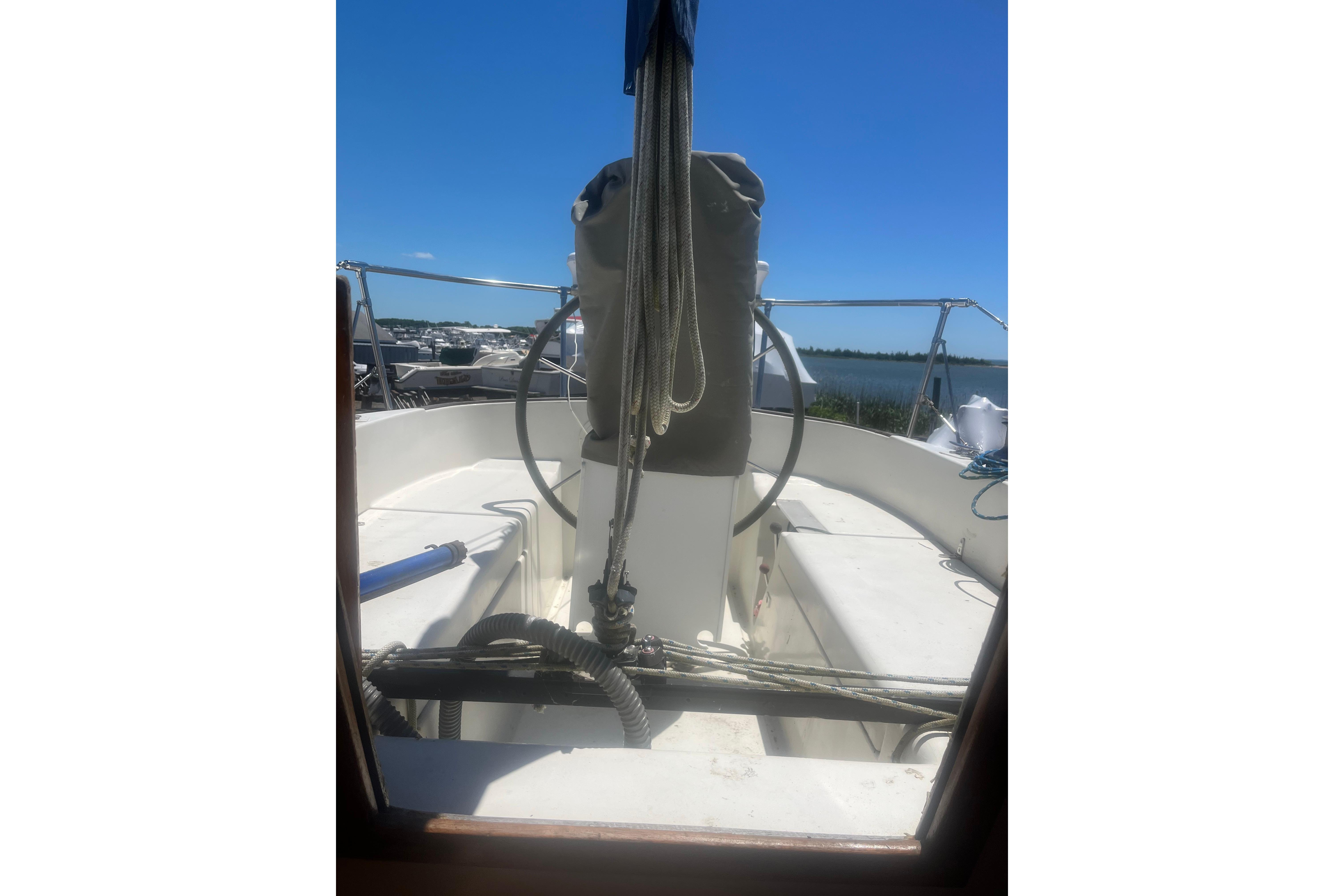 1972 C&C 30 sailboat cockpit with steering wheel, ropes, and clear blue sky.