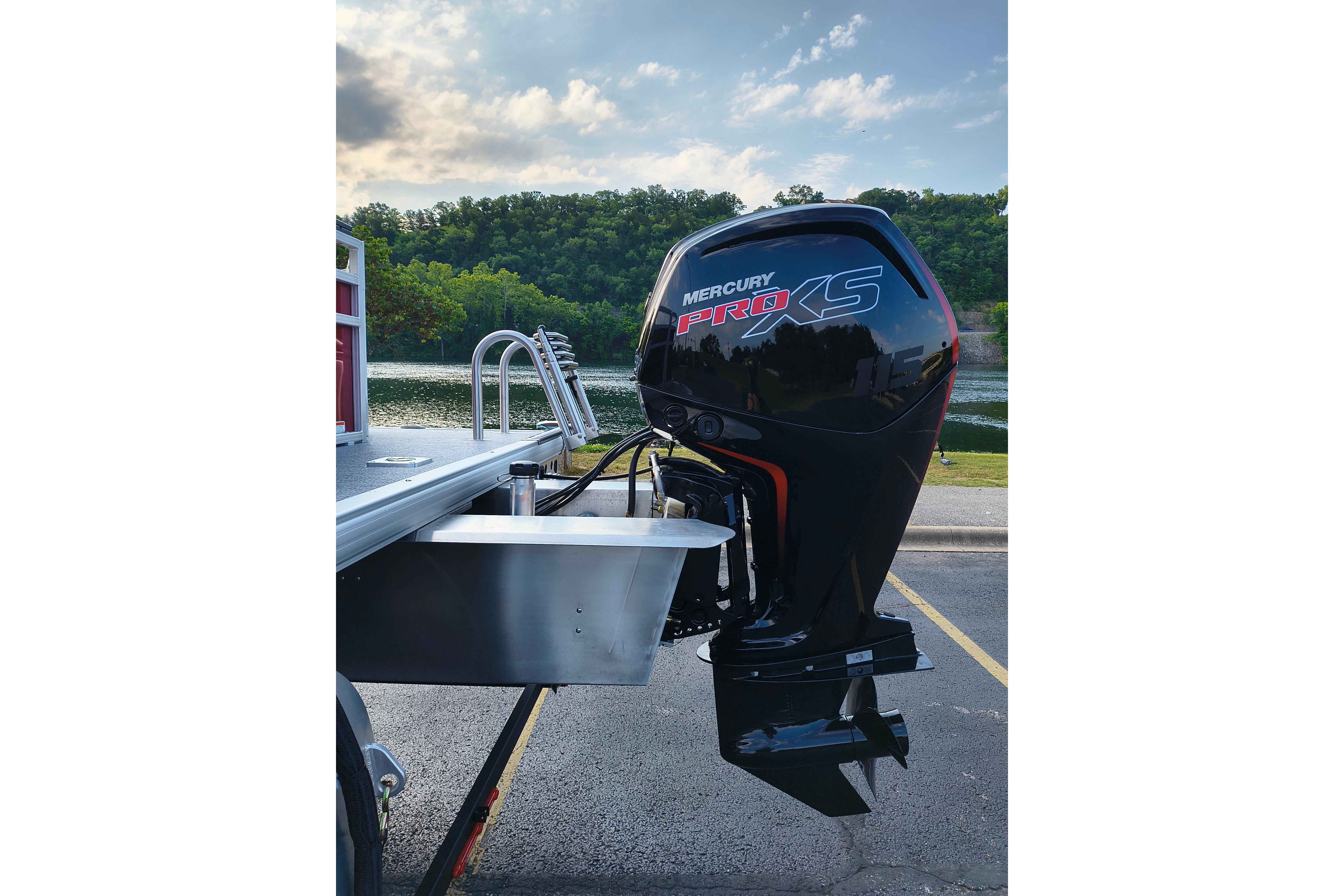 2026 Sun Tracker Fishin' Barge 22 DLX with Mercury Pro XS outboard motor by a scenic lake.