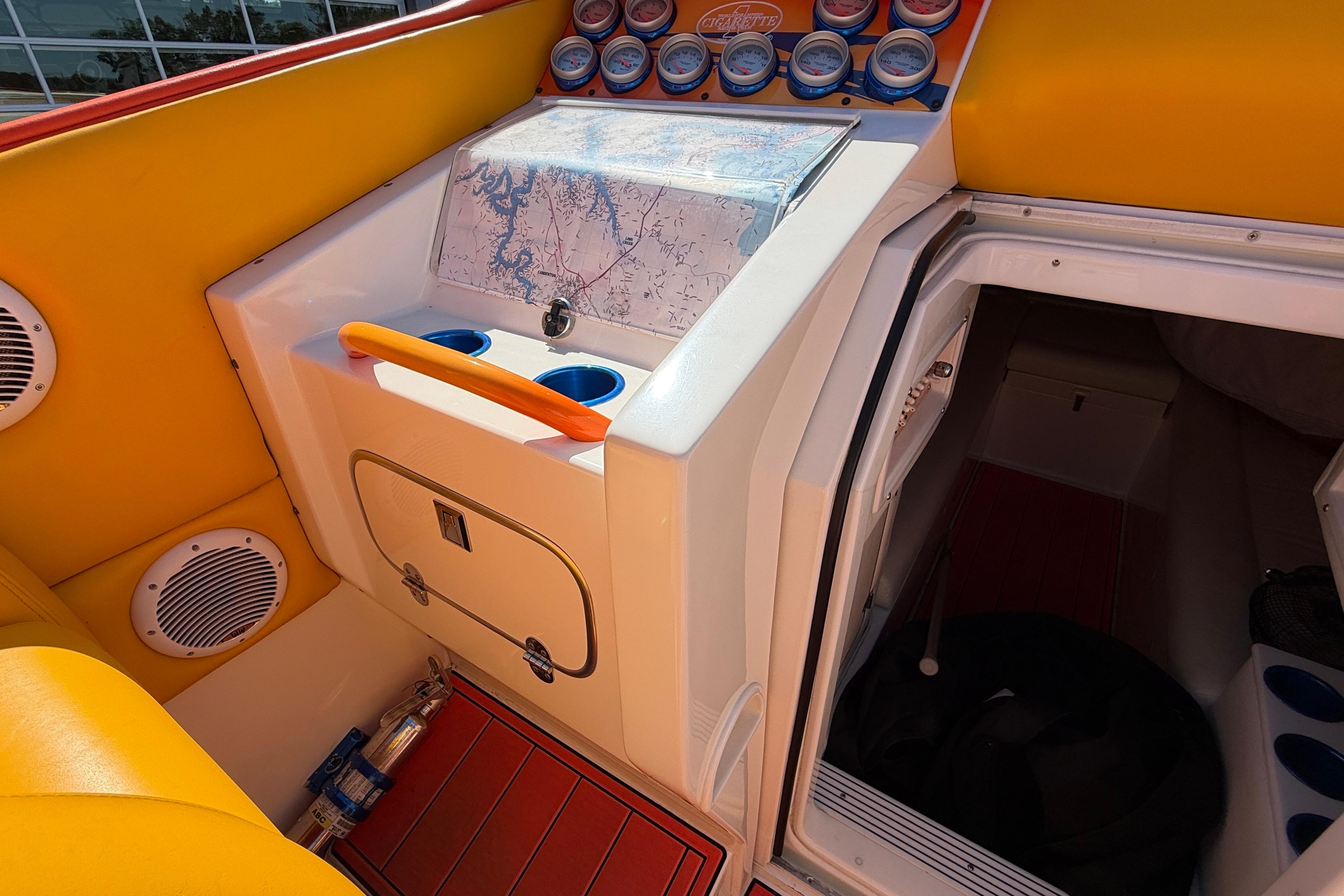 Interior of a 2002 Cigarette 35' Cafe Racer boat with vibrant yellow seating and control panel.