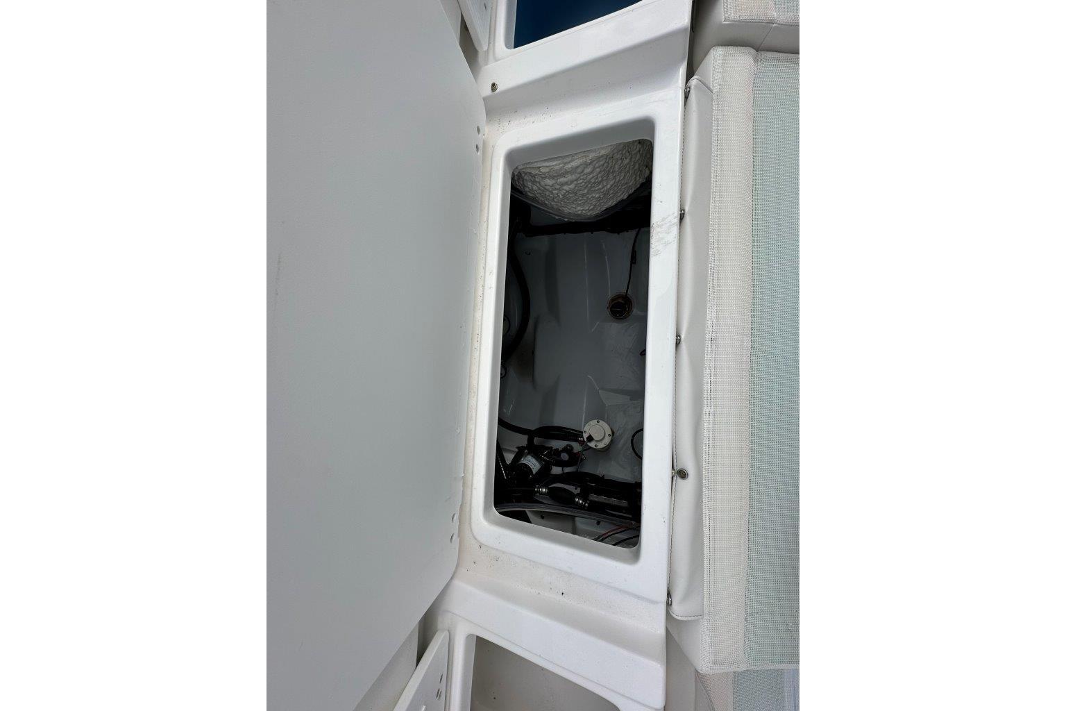 Open storage compartment on 2026 Tidewater 272 LXF boat, showcasing interior details.