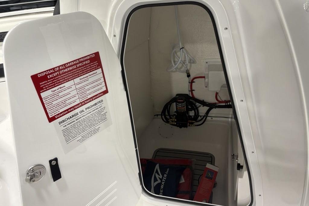 Open storage compartment in 2026 Tidewater 232 CC Adventure boat, showing safety equipment and wiring.