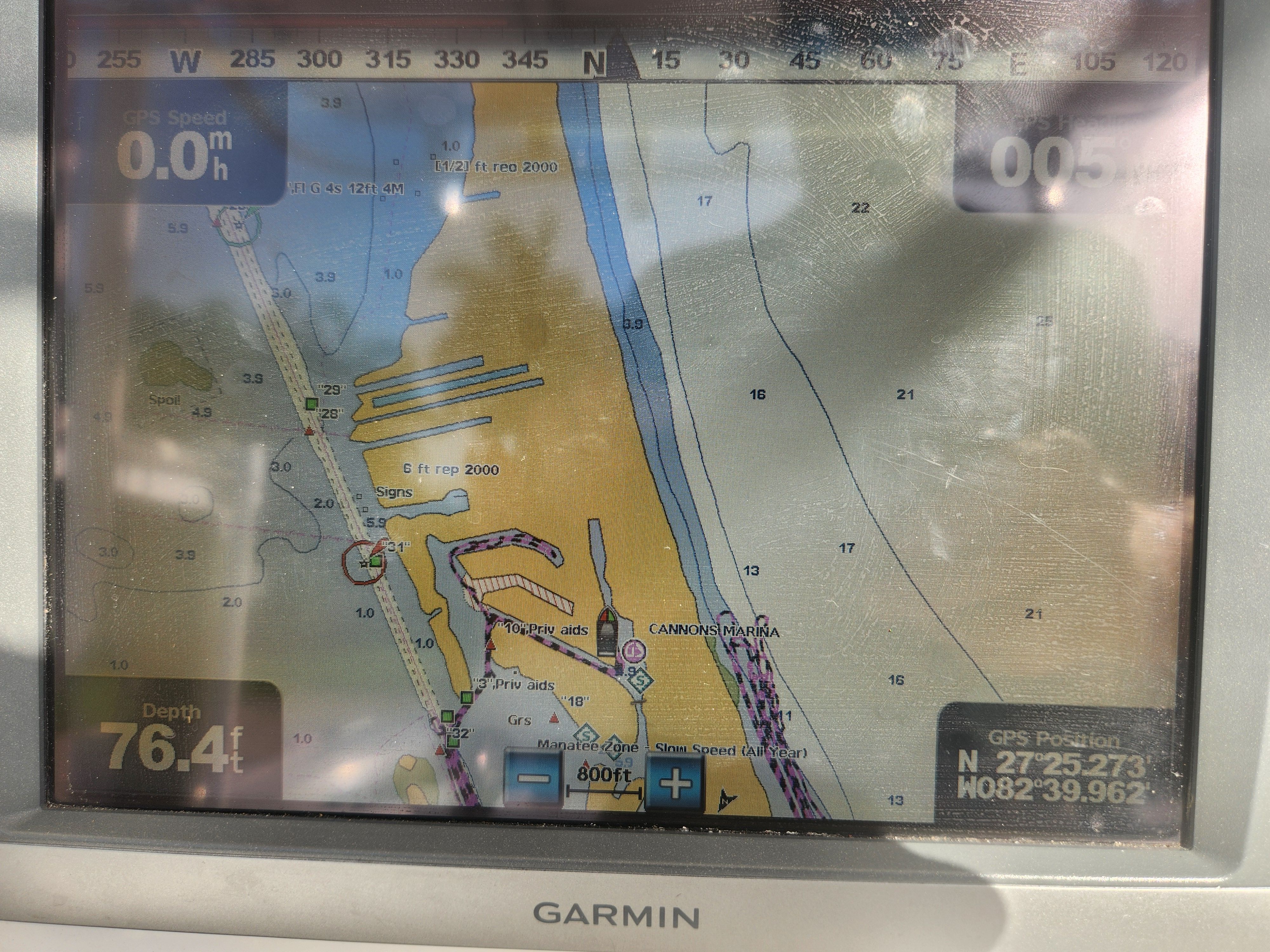 A Garmin navigation system displays a nautical chart with depth readings and GPS position.