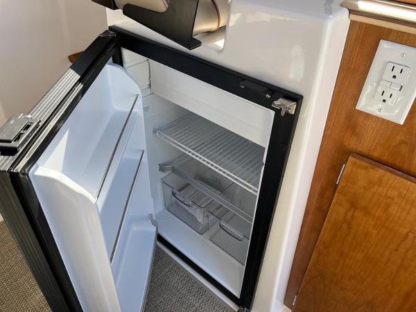 Compact refrigerator inside 2025 Cutwater C-248 C Coupe boat, open with shelves visible.