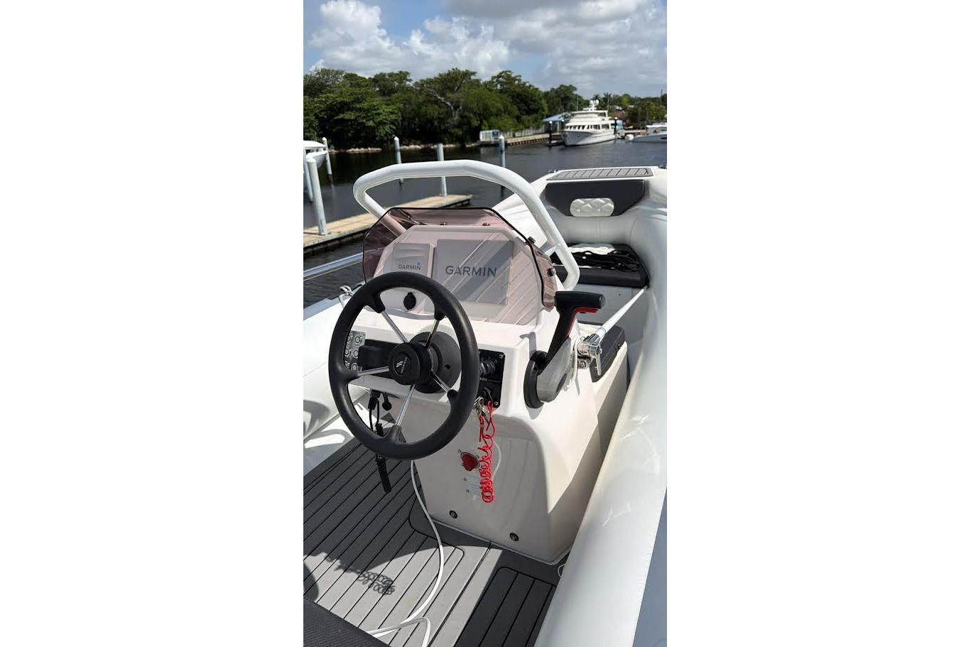 2022 Highfield Sport 420 boat cockpit with Garmin navigation system, docked by a scenic waterway.