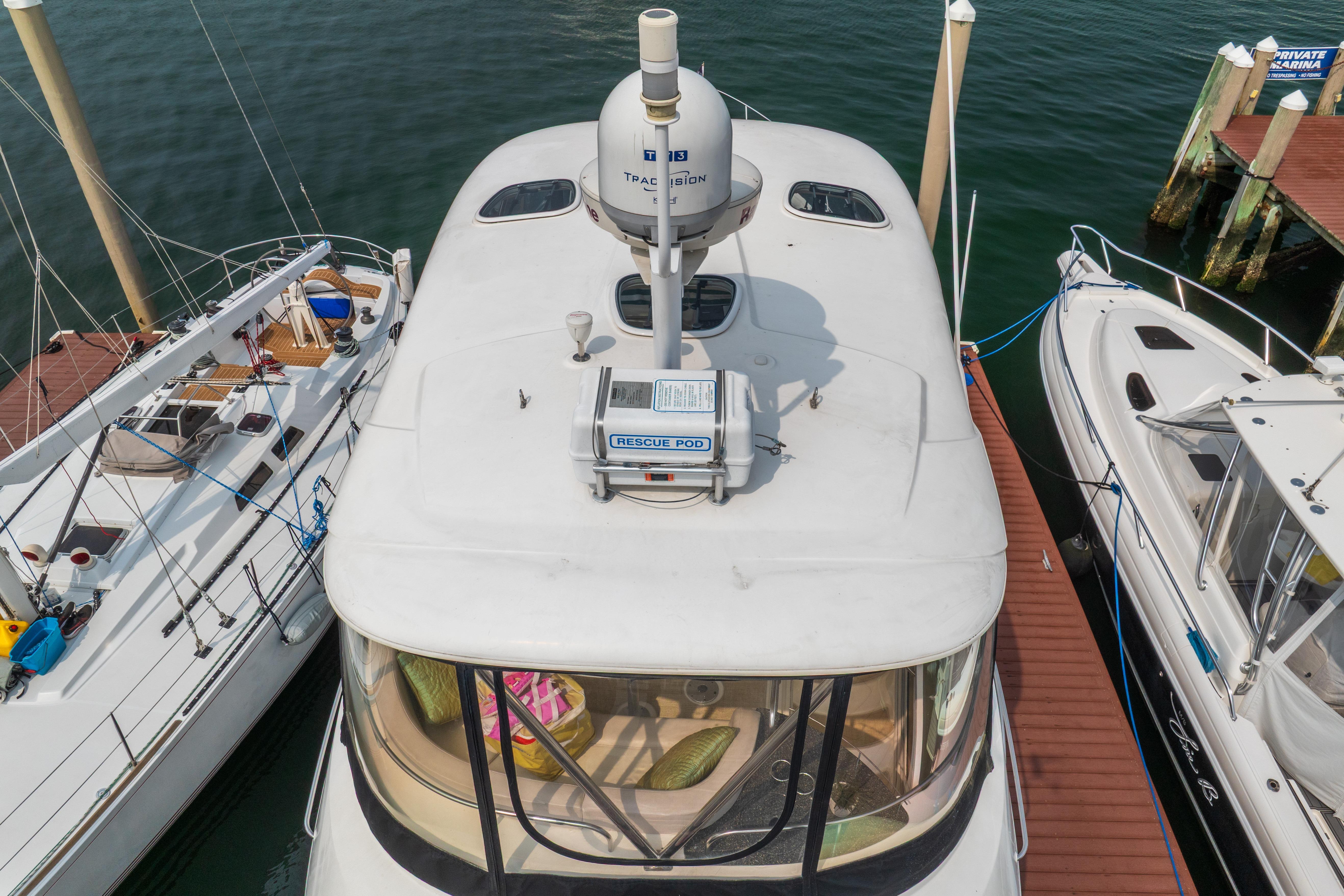 2009 Meridian 441 Sedan yacht docked between two boats at a marina.