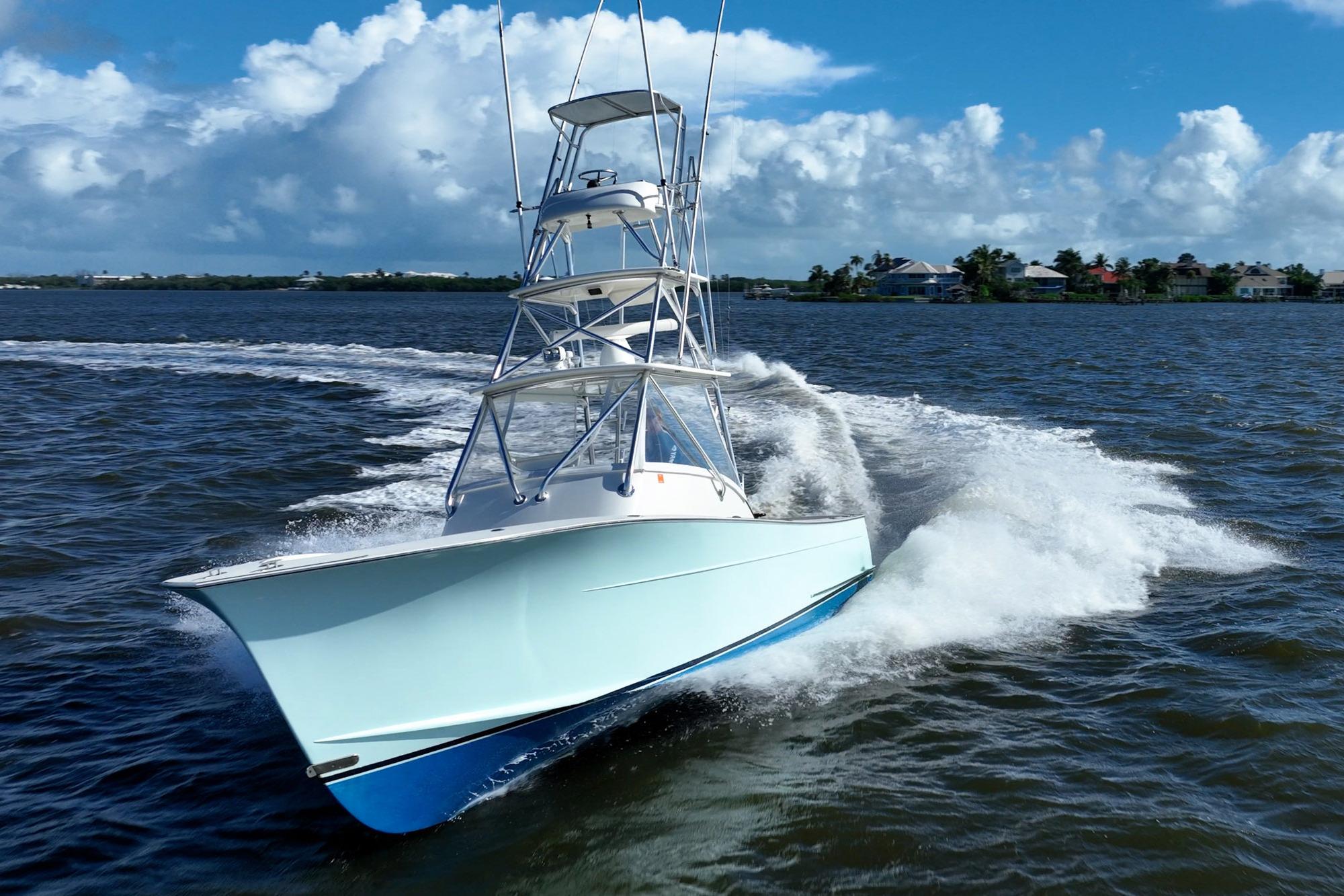 2003 Gamefisherman 34 Express boat cruising on open water under a clear blue sky.