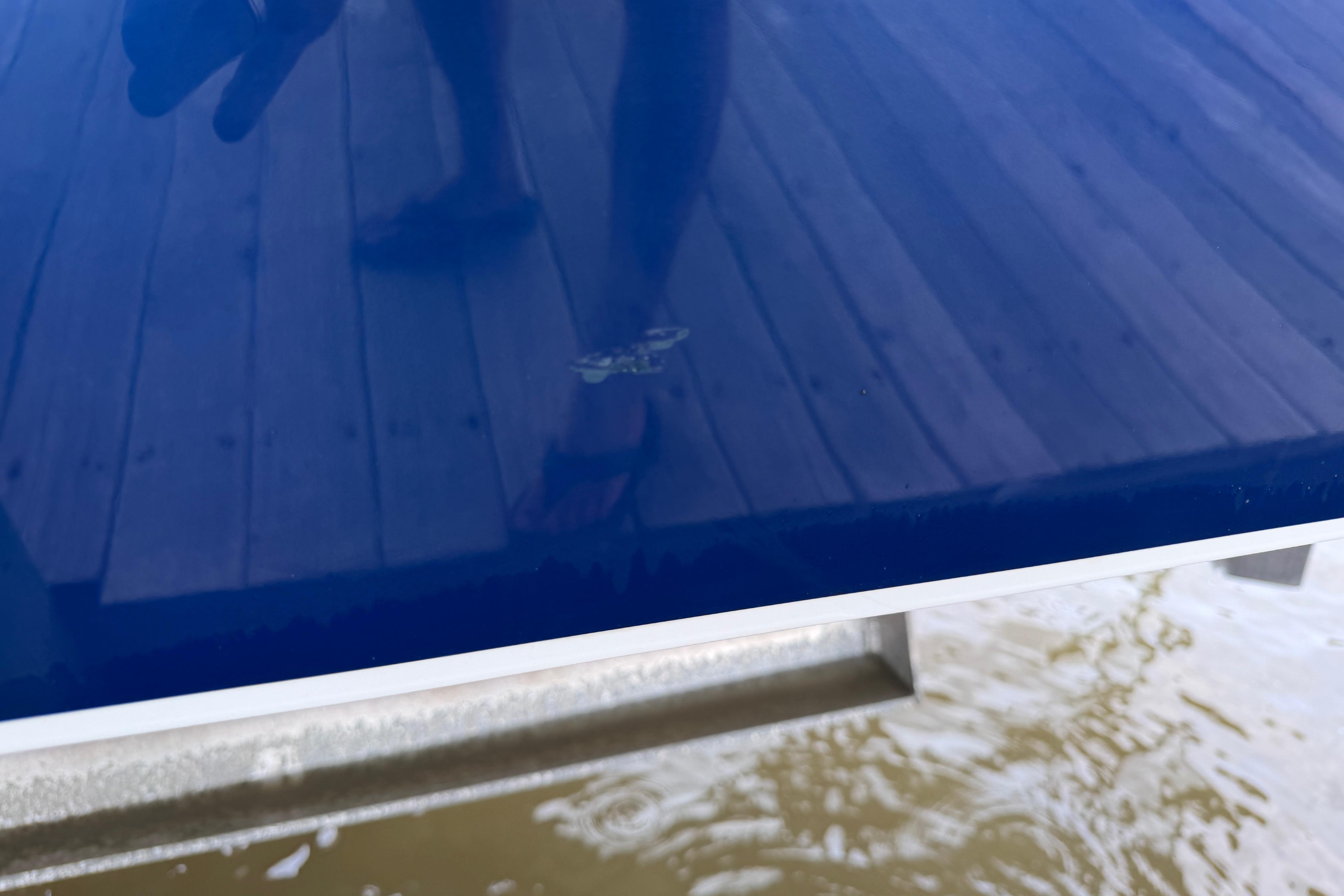 Blue hull of 2013 Nor-Tech 477 SPX Vee Bottom boat reflecting dock and water.