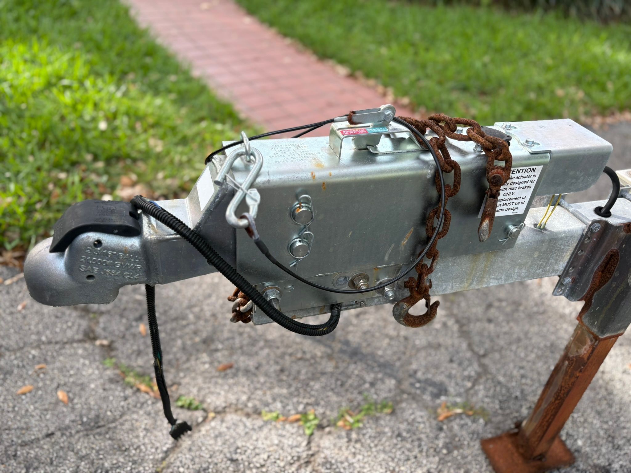 Close-up of a boat trailer hitch with a rusty chain on asphalt.