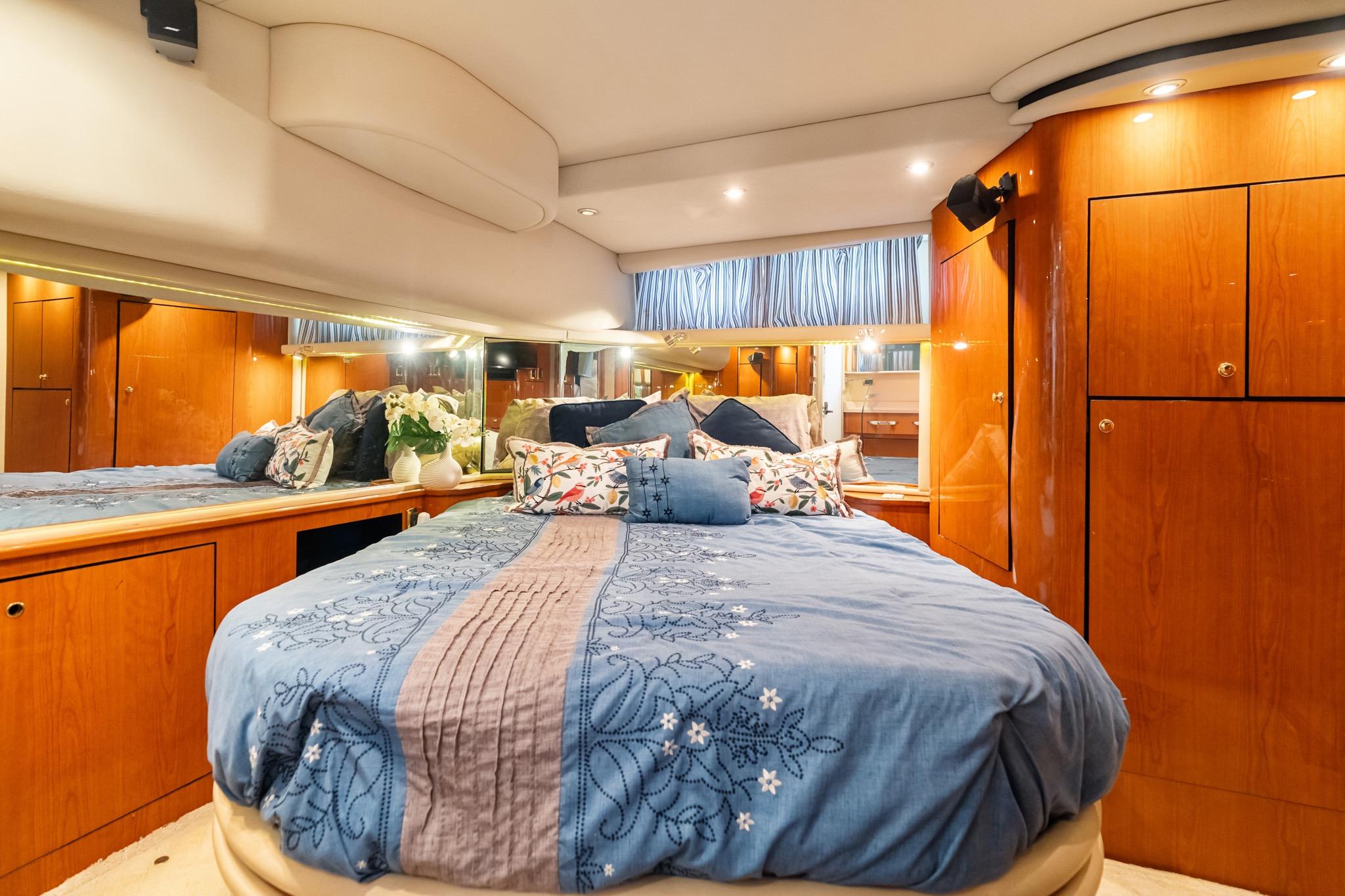 Luxurious bedroom interior of 2001 Sea Ray 540 Cockpit Motor Yacht with elegant wood cabinetry.