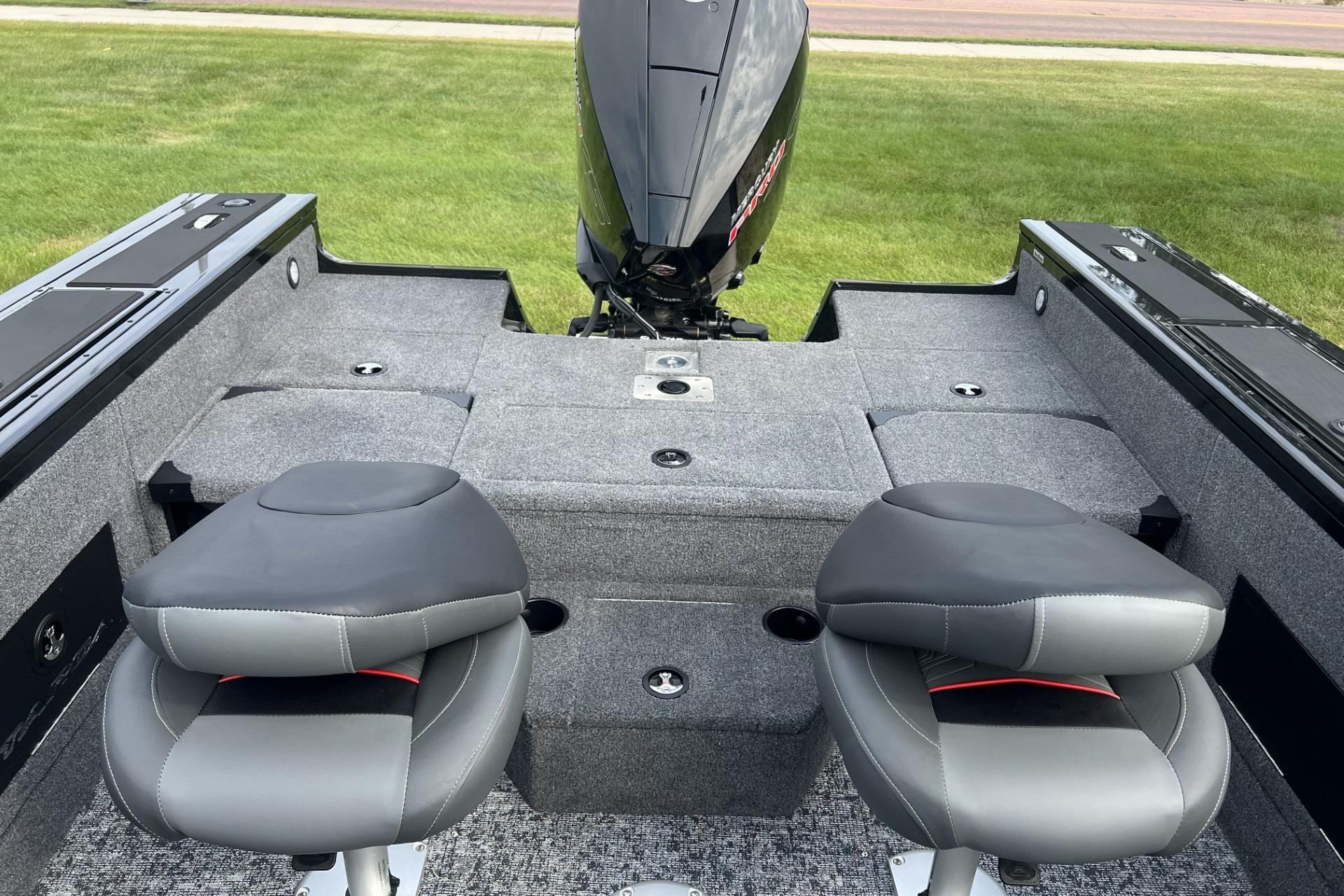 2025 Tracker Targa V-18 Combo boat interior with two seats and motor, on grass.