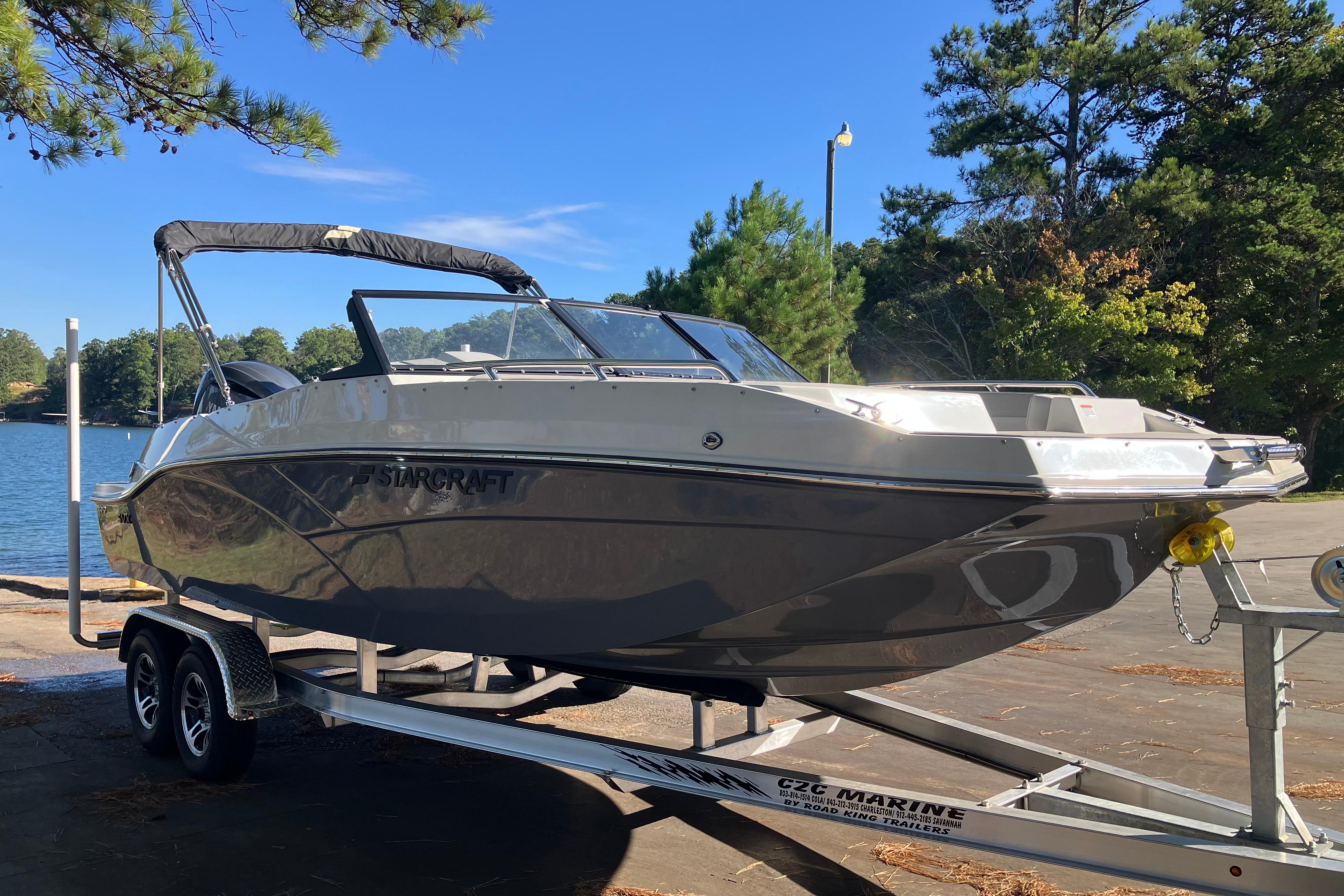 2025 Starcraft SVX 210 OB boat on trailer by a scenic lake.