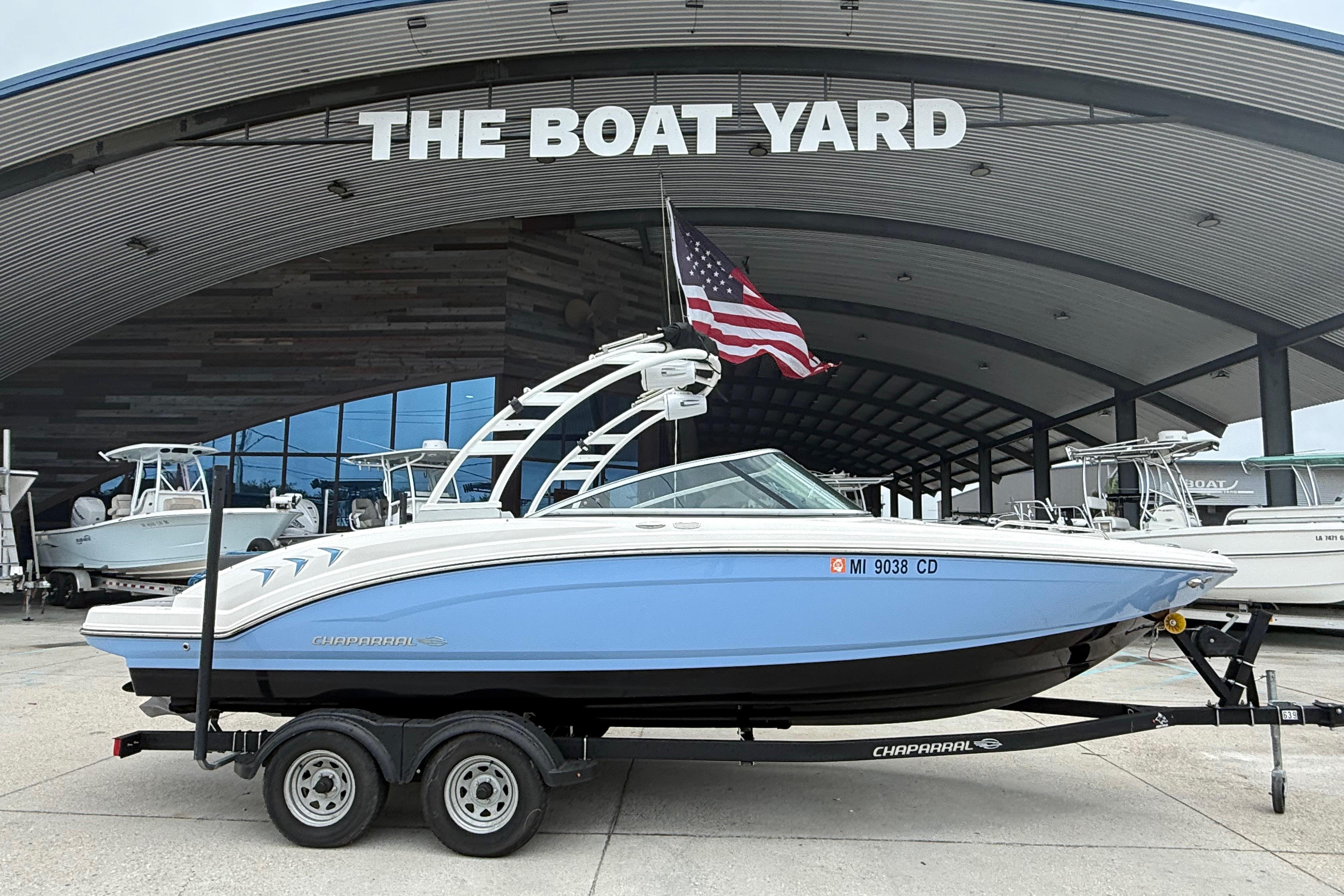2023 Chaparral 230 SSi boat on trailer at The Boat Yard, displaying American flag.