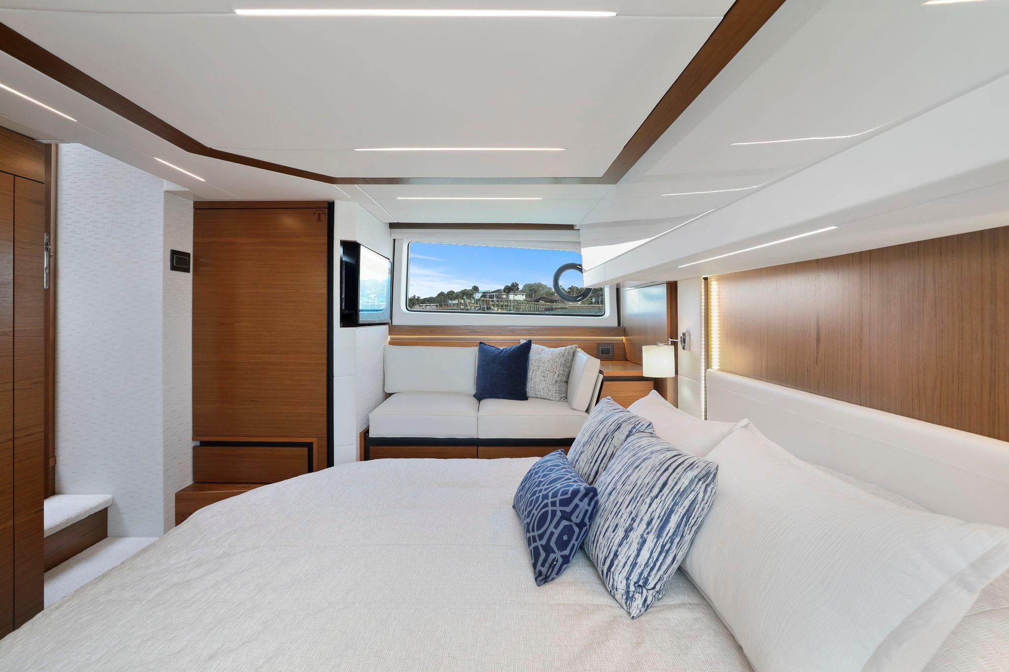 Luxurious interior of 2023 Tiara Yachts C49 Coupe with elegant bedding and scenic window view.