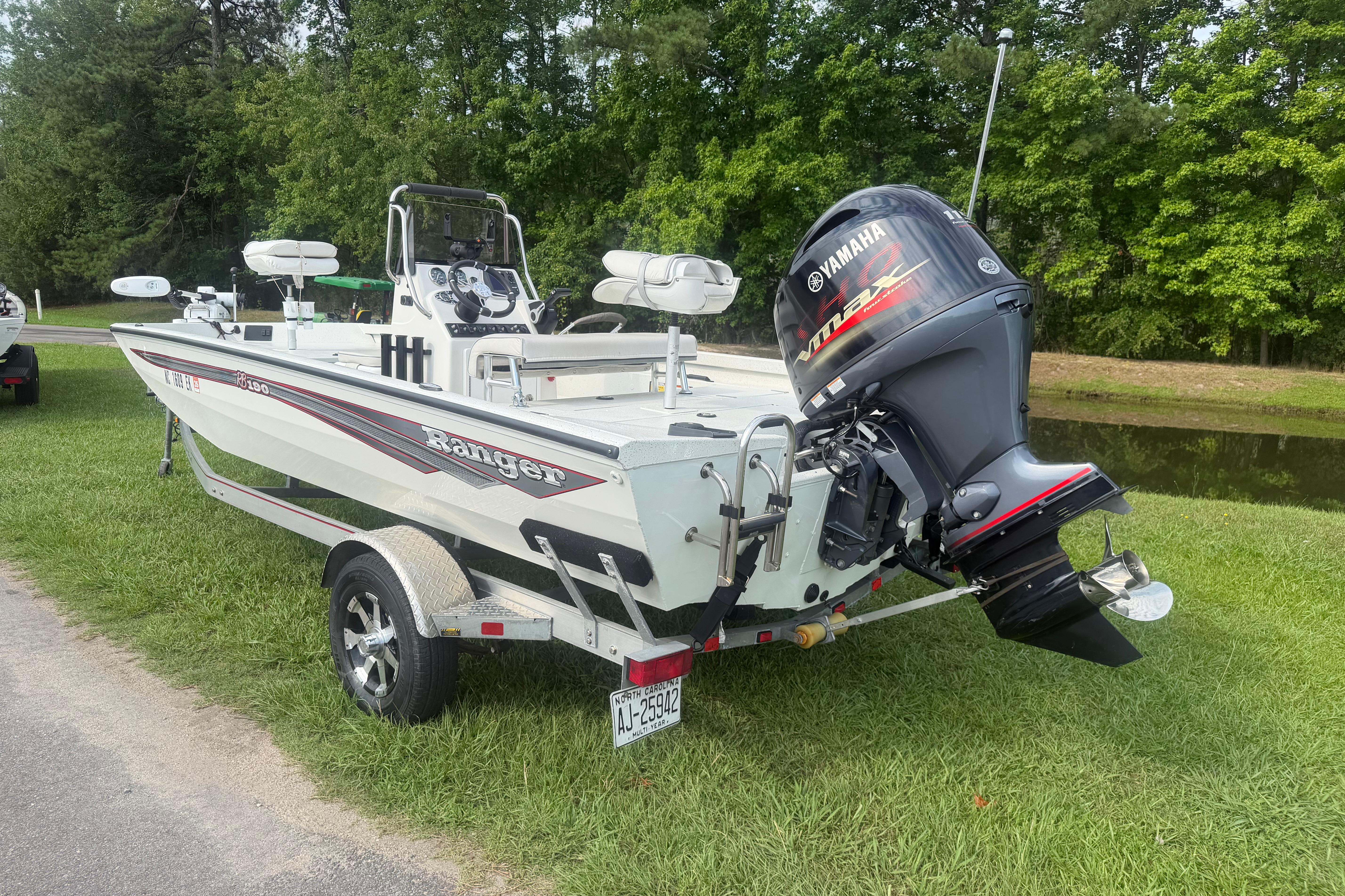 2018 Ranger RB190 boat with Yamaha outboard motor, parked on grass near a pond.