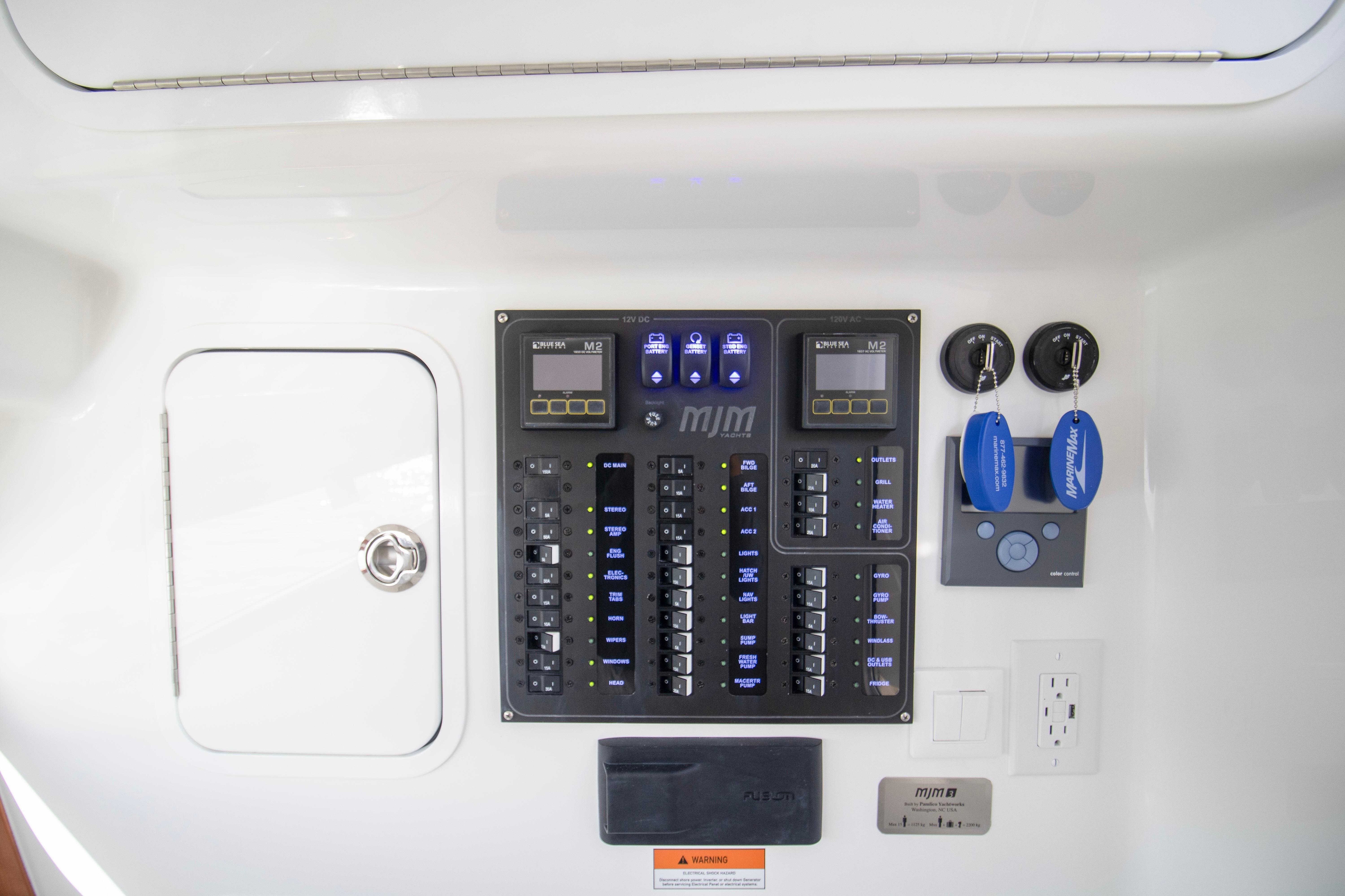 Control panel of 2025 MJM 38 X boat with switches and key fobs.