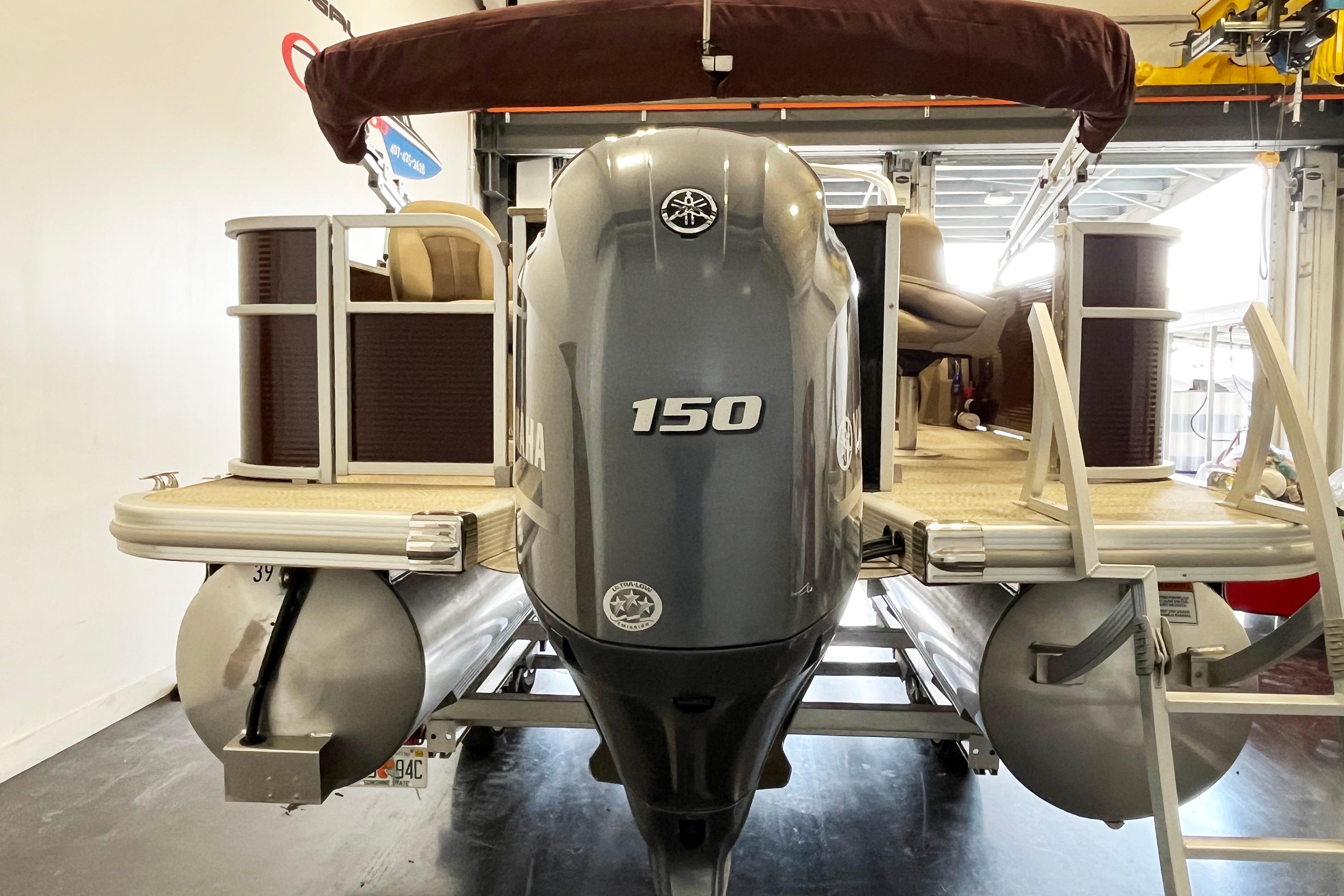 2020 Bennington SX25 pontoon boat with Yamaha 150 outboard motor in a garage.