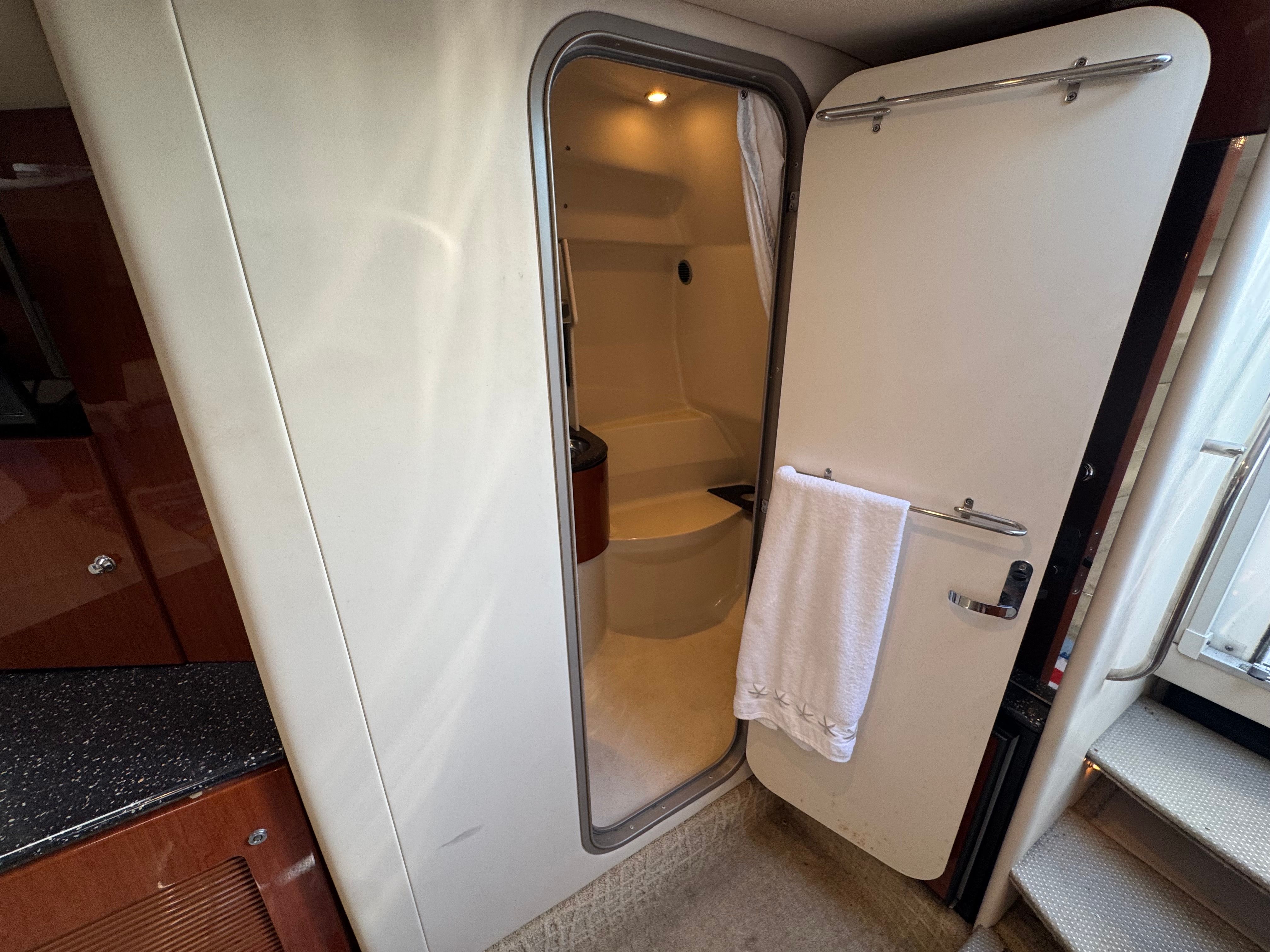 Interior of a yacht with an open bathroom door and towel.
