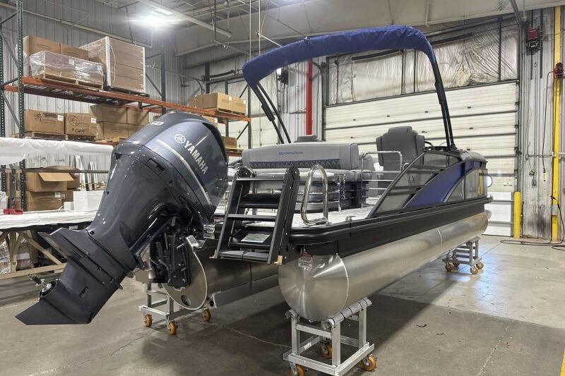 2026 Bennington 23 LXS Swingback pontoon boat with Yamaha engine in a warehouse setting.