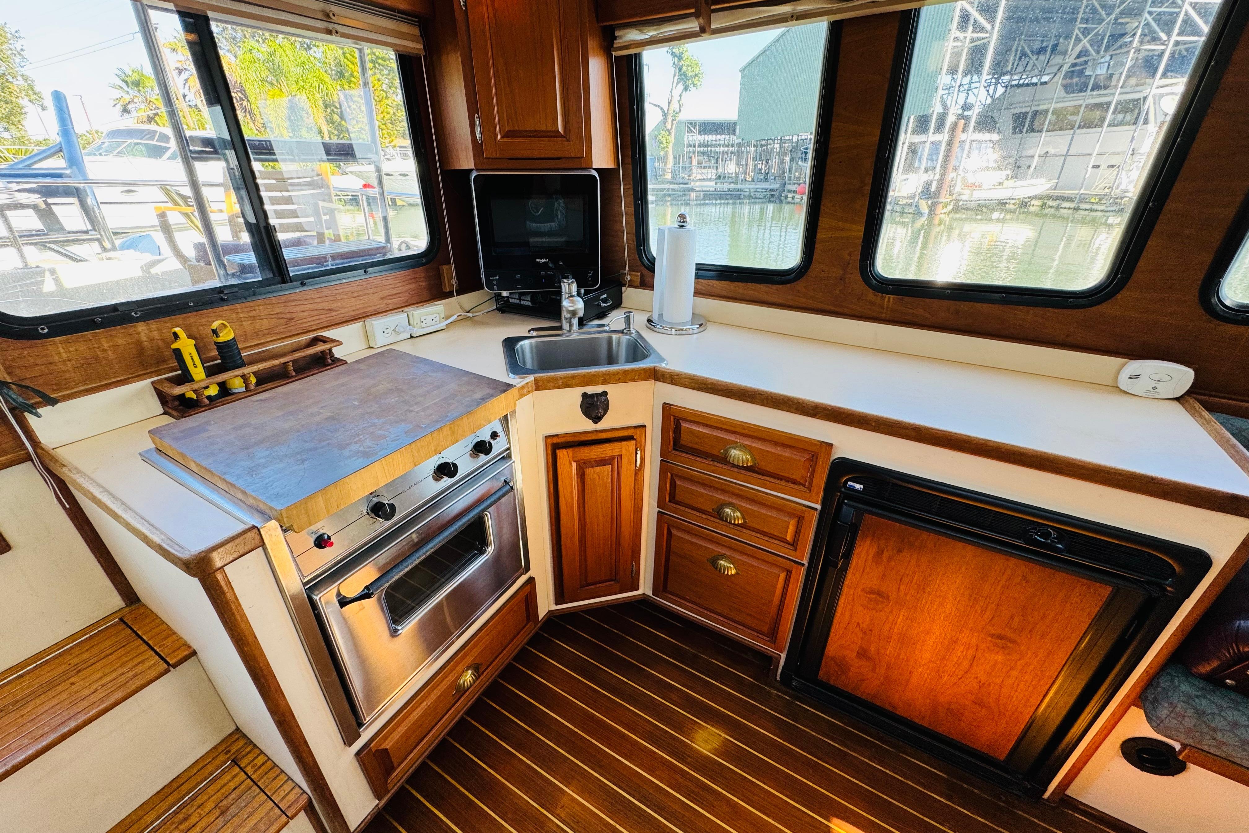 Cozy kitchen area in a 1996 Nordic Tug 32, featuring wood cabinetry and modern appliances.
