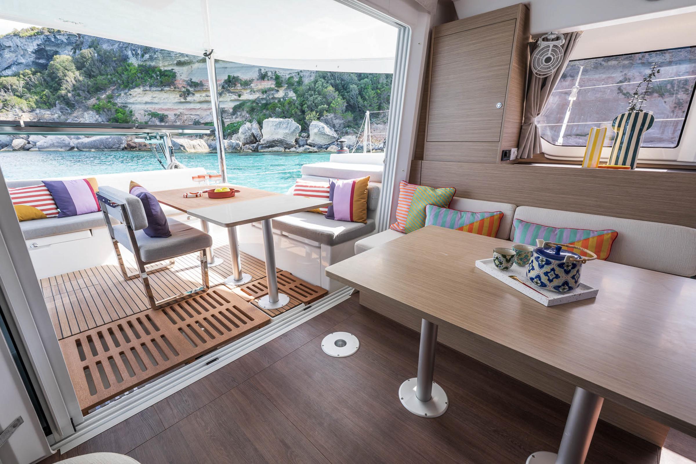 Luxurious interior of 2025 Lagoon 38 catamaran with colorful cushions and scenic ocean view.